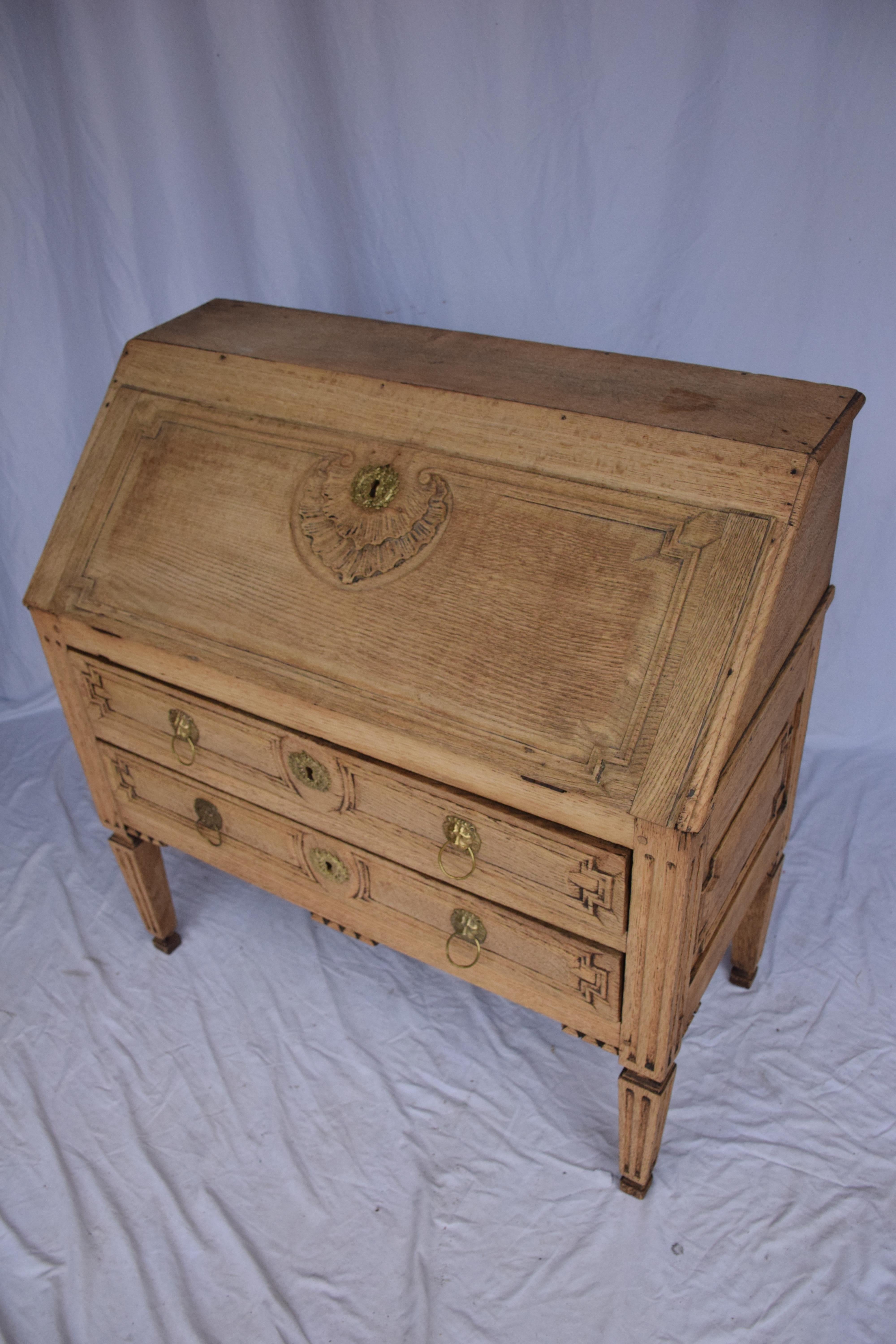 19th century bleached oak drop front secretary. A pair of drawers aligned neatly beneath a drop-front writing section.  When the writing surface is pulled down, the interior drawer system is revealed. This piece looks equally at home in a living