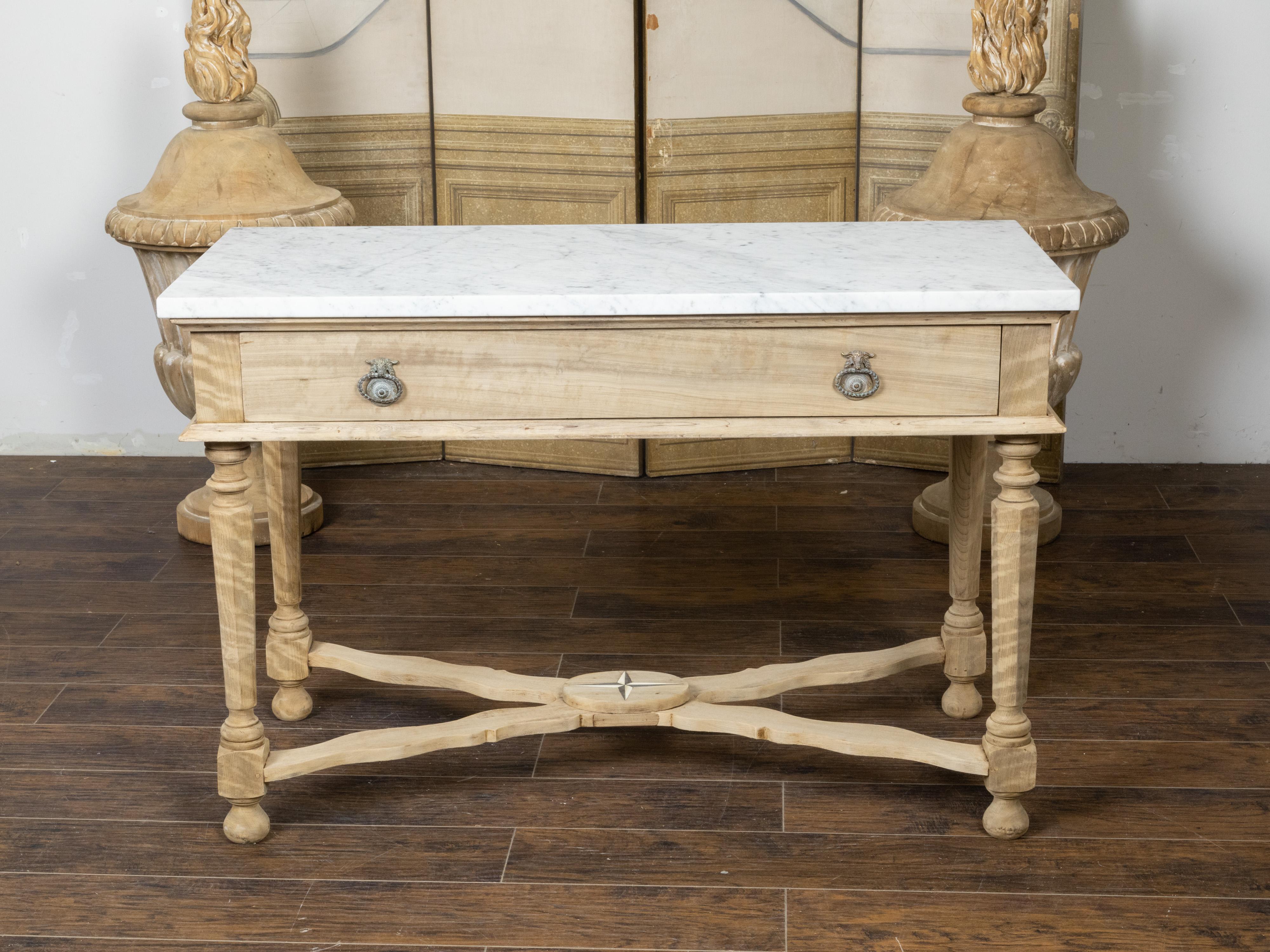 A Continental bleached walnut console table from the 19th century, with white marble top, long single drawer, faceted tapering legs and X-Form cross stretcher. Created in Continental Europe during the 19th century, this console table features a