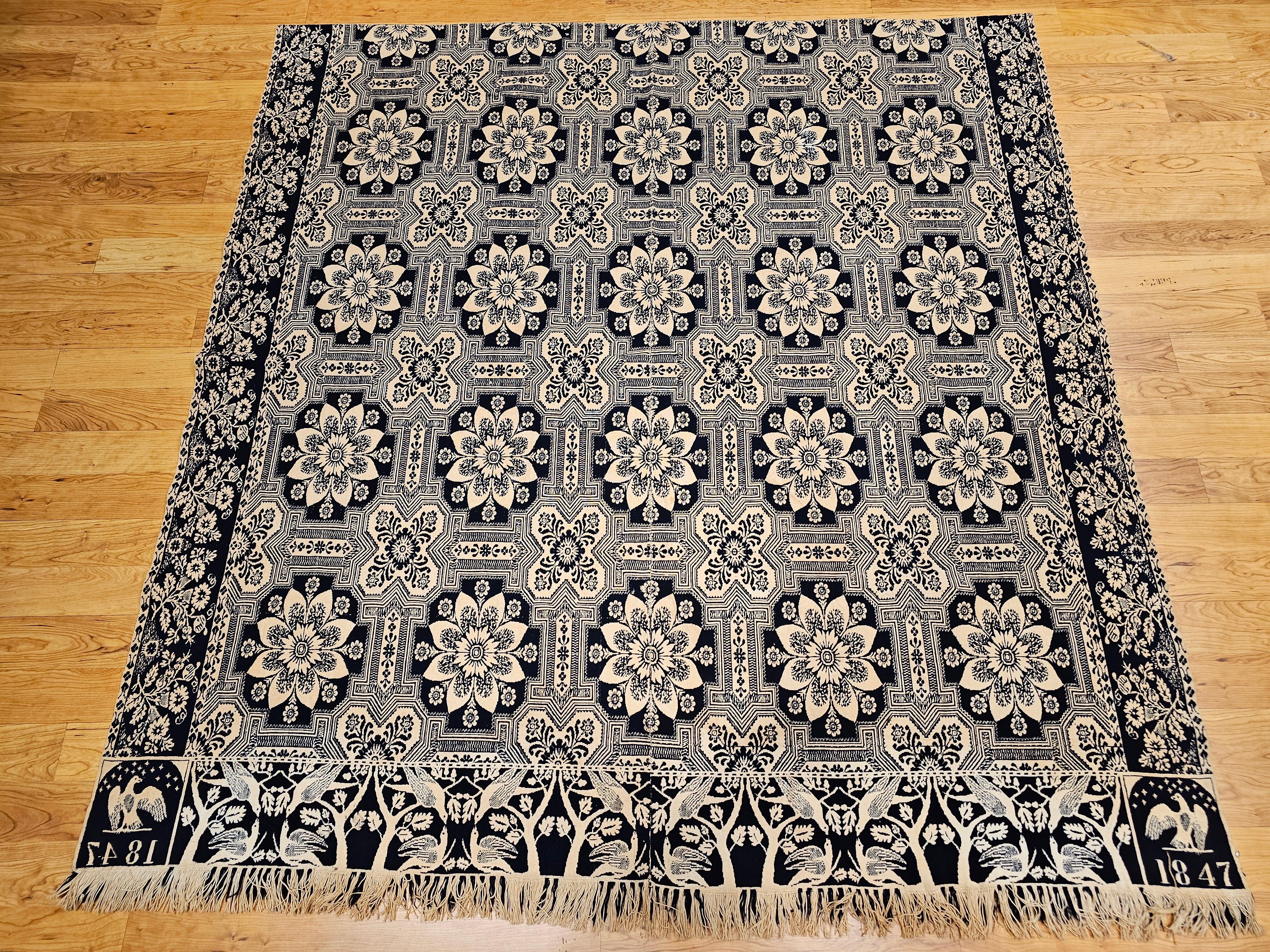 A striking example of American textile artistry, this mid-19th century blue and white Jacquard coverlet is dated 1847 and showcases rich patriotic and natural symbolism. The central field features repeating floral medallions, while the border is