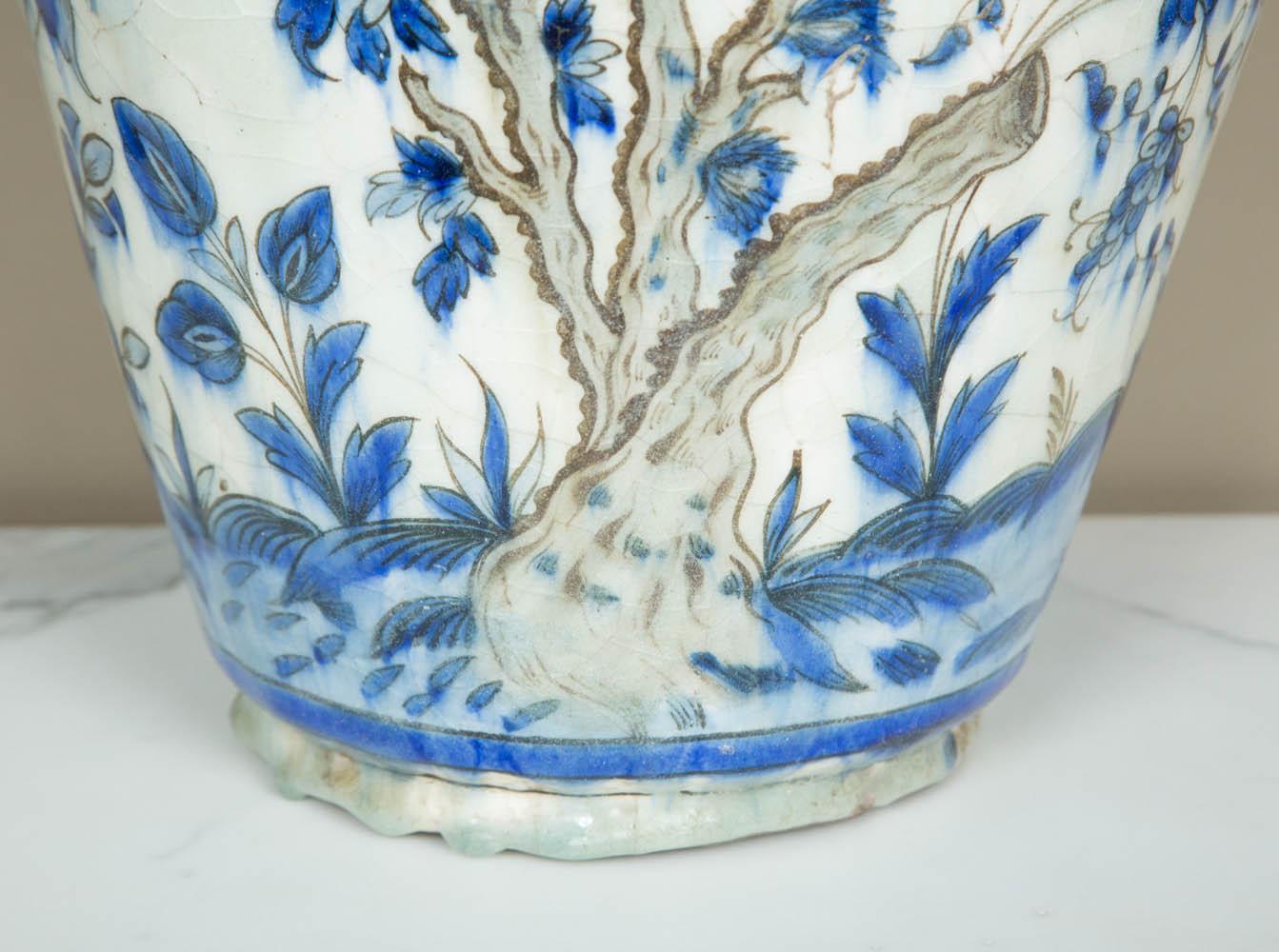 A Qajar (1794-1925) blue and white jar
Persia, 19th century, circa 1840-1960.
Underglaze blue painted fritware, on white ground with black outlines, depicting tree branches and scrolling flowers. Beautiful heavy drops of glaze at the bottom (see