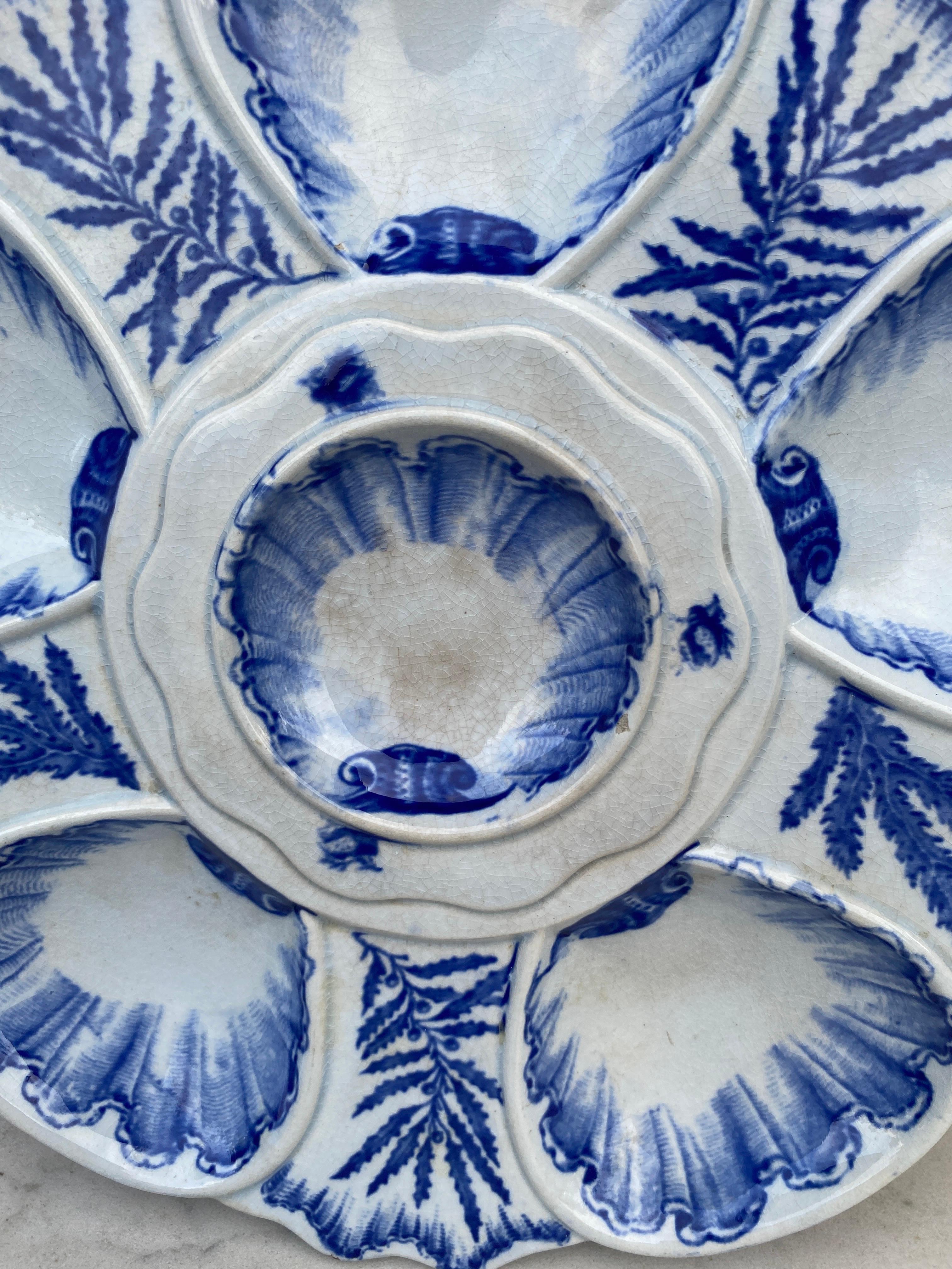 Elégante assiette à huîtres bleue et blanche signée Bordeaux Vieillard, vers 1890.
Six puits entourés d'algues bleues de différentes sortes.