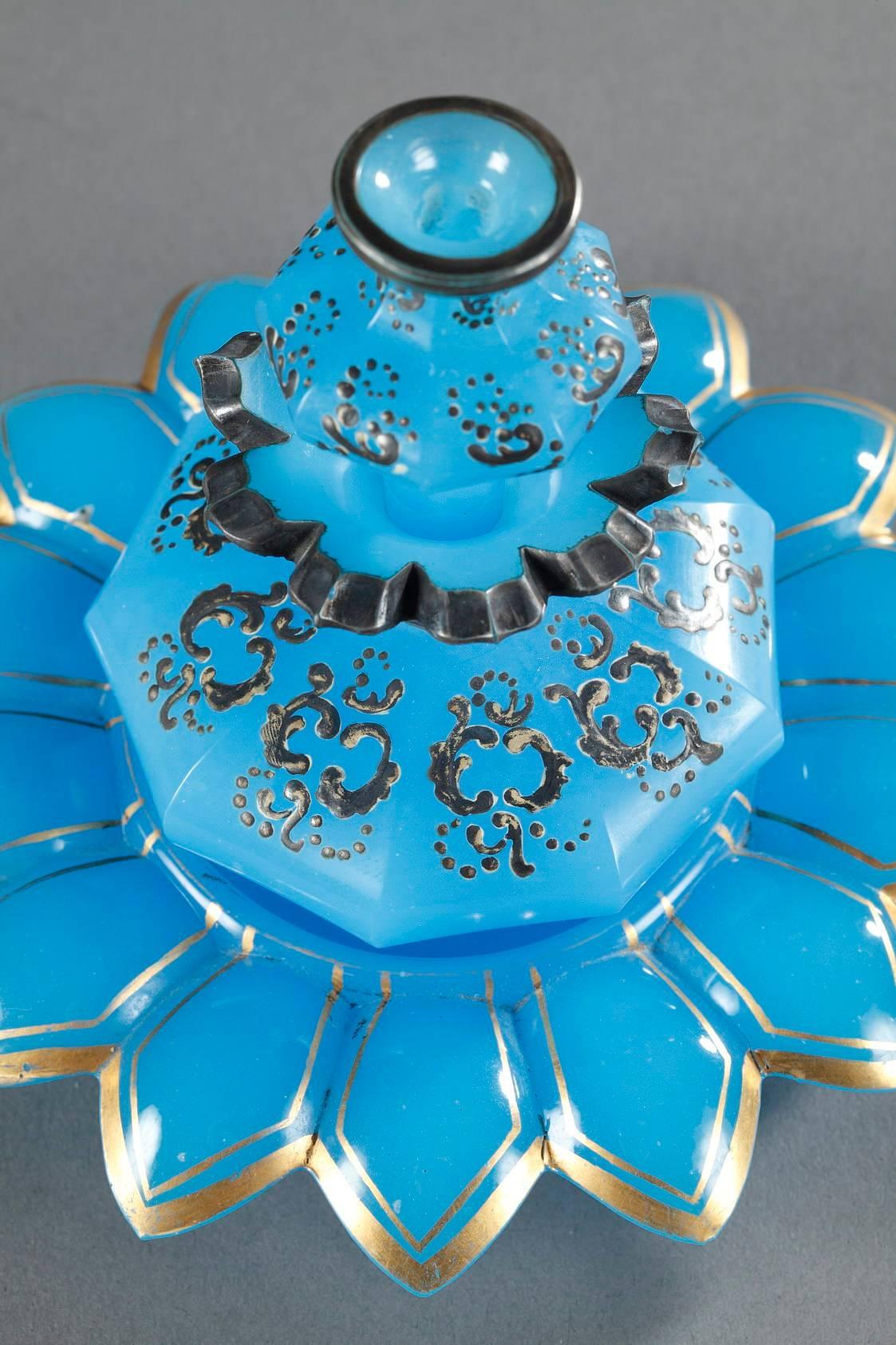 Mid-19th century blue, opaline crystal set composed of a small flask, its stopper and a small, flower-shaped cup. The perfume bottle and flask are decorated with enameled and silver stylized rinceau, and the cup is highlighted with gilding. Light