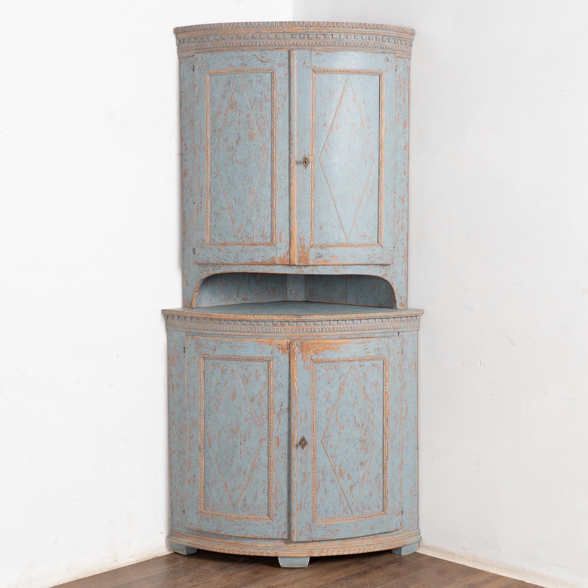 This bow front pine corner cabinet has a blue hand-painted finish with diamond panels, dentil molding and egg and dart details.
The blue painted finish has a soft, worn patina which has been lightly scraped and gently distressed revealing the