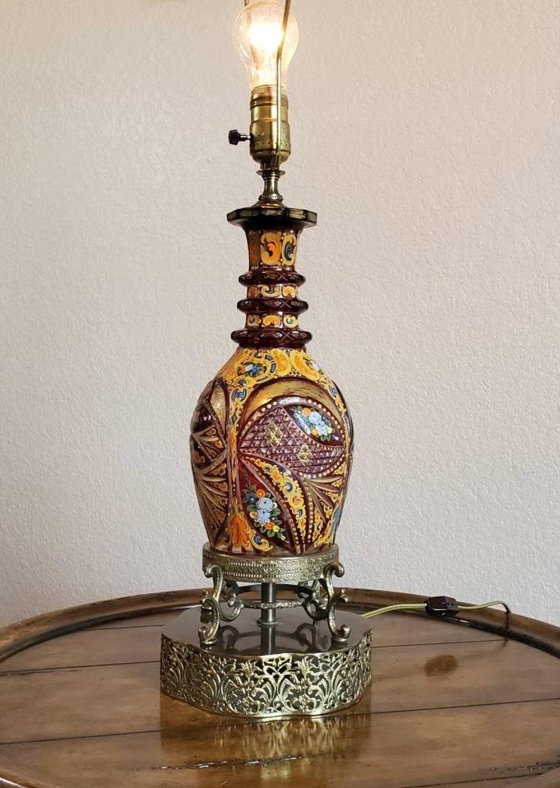 An opulent Bohemian ruby cased and polychrome enameled cut glass decanter from the 19th century, now fashioned as a table lamp. Exquisitely handcrafted and detailed for the Islamic market, having Middle Eastern design influence, with a ring neck,