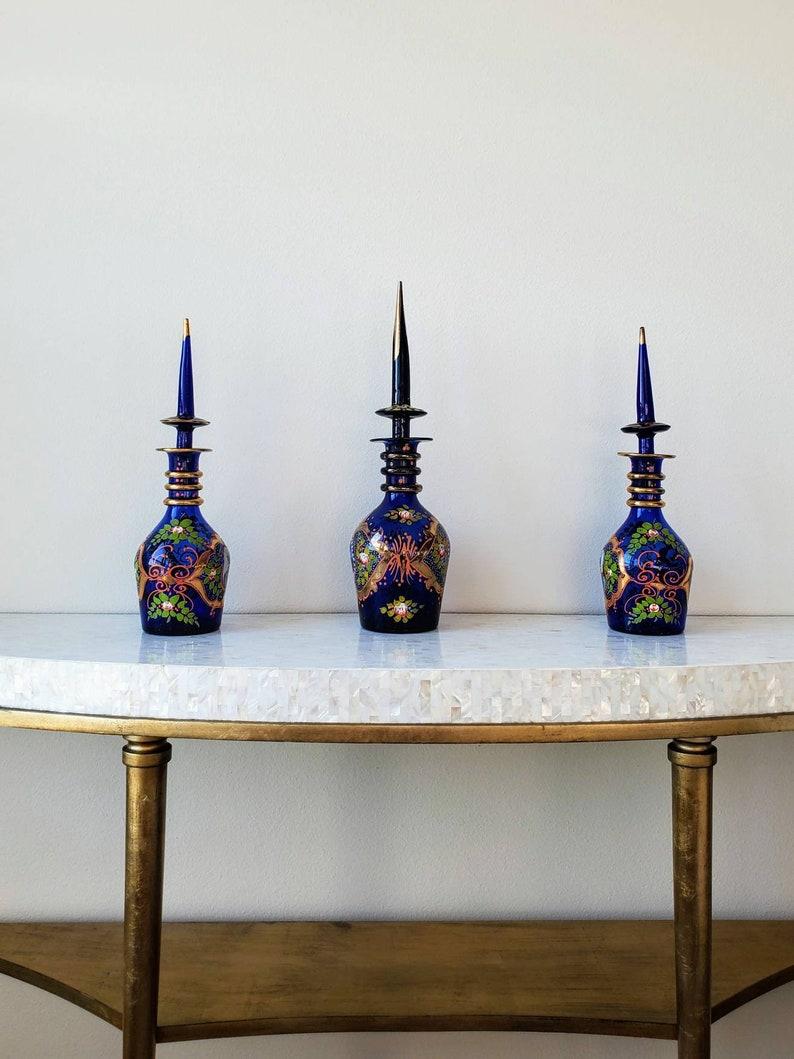 A scarce set of three fine quality Bohemian enameled cobalt art glass decanters, exquisitely made for the Persian market, during the late 19th century. 

Hand-crafted in Bohemia (present day Czech Republic) by some of the world's best glass