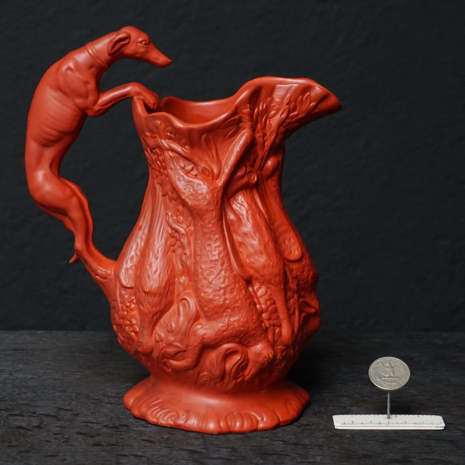 Pichet en terre cuite peint avec des détails étonnamment brillants, fabriqué par l'usine Ferdinand Gerbing Werke vers 1850-1860.

Très jolie cruche en terre cuite peinte en rouge-orange vif représentant un thème de chasse, avec un chien whippet