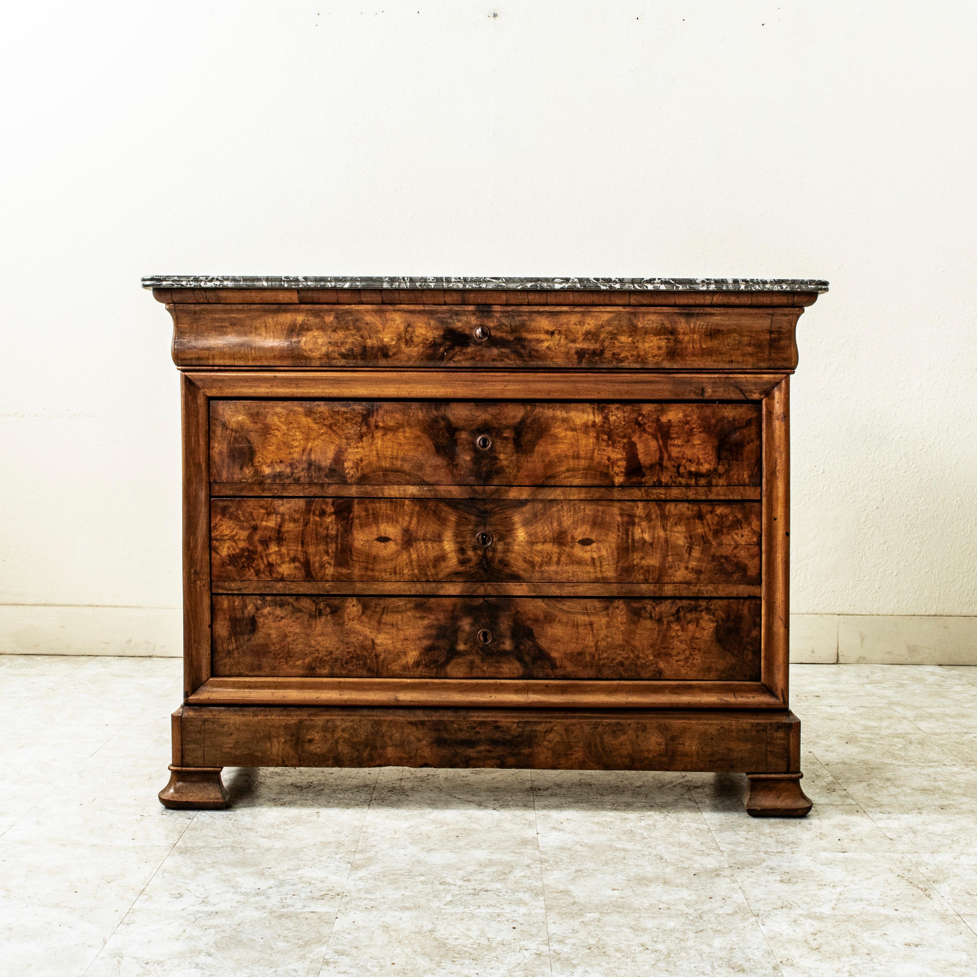 Questa commode o cassettiera d'epoca Louis Philippe mostra l'esemplare maestria del XIX secolo con una facciata in radica di noce e fianchi a pannelli in noce massiccio. Il pezzo è sormontato da un piano in marmo Saint Anne a doppio smusso. Un unico