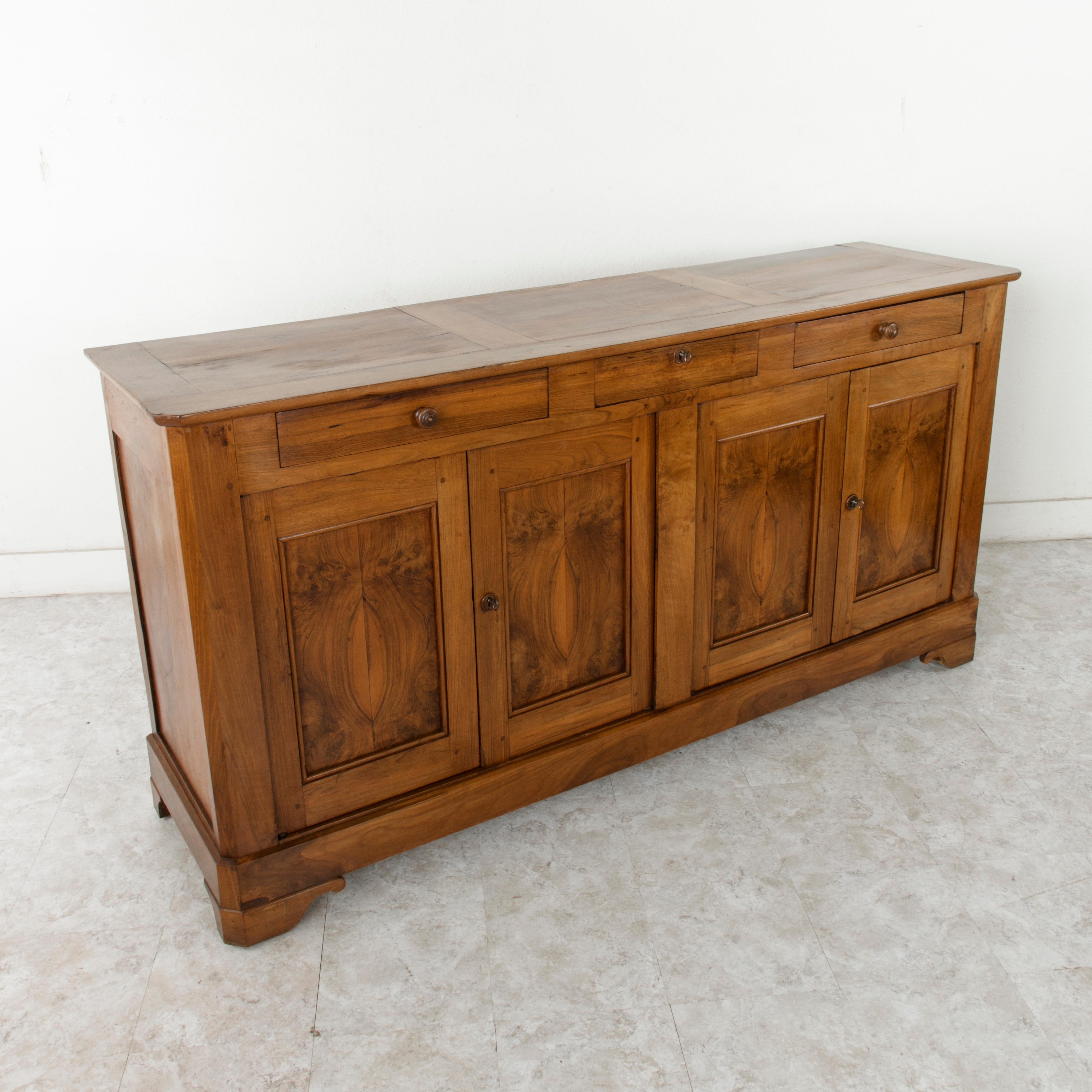 This French Louis Philippe style enfilade or sideboard from the late 19th century is constructed of solid walnut with hand pegged joinery. This server features four doors of bookmatched solid walnut panels that conceal two compartments, each with a