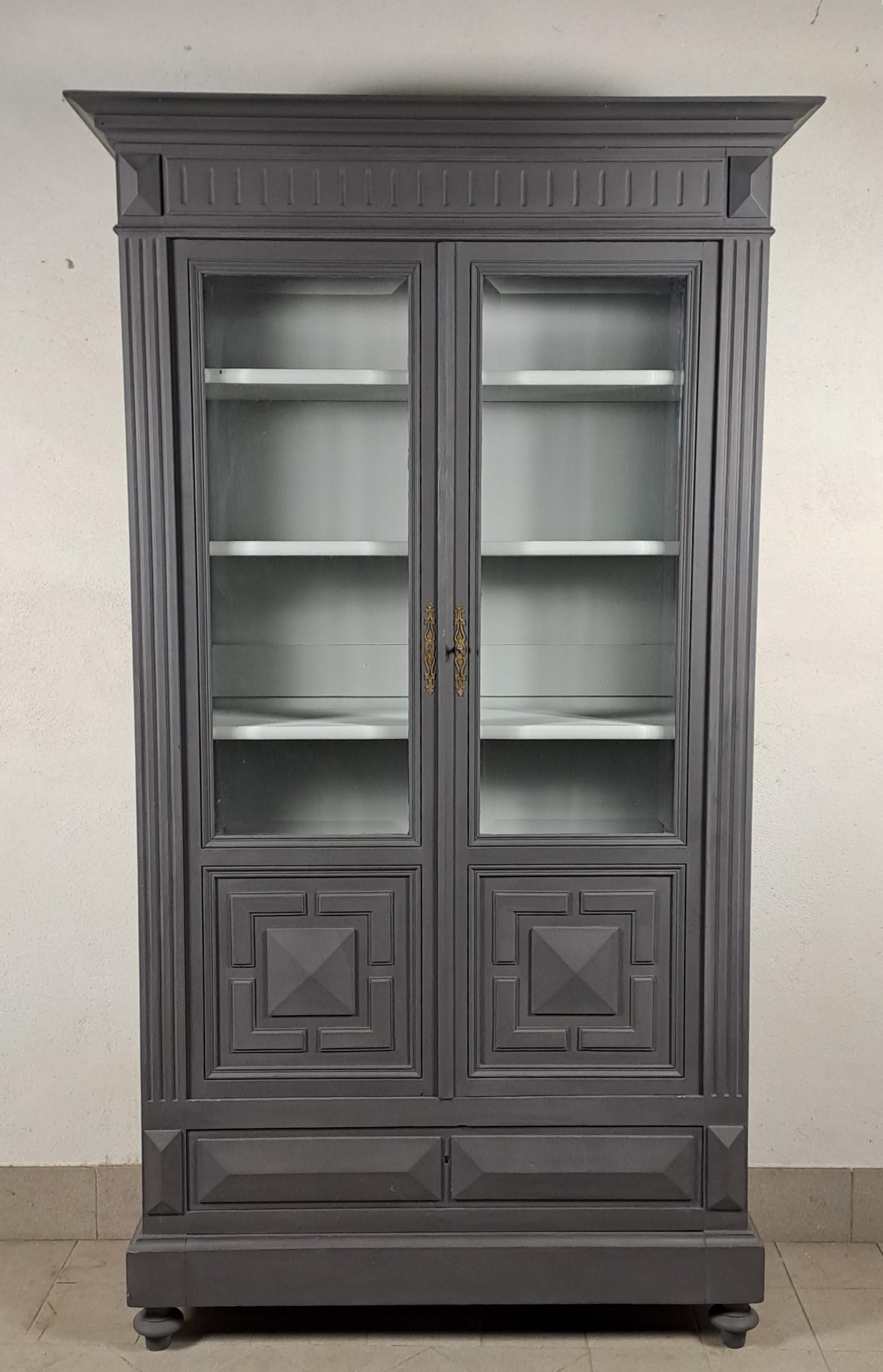 Libreria in legno laccato grigio e interno bianco con apertura a due ante con vetro smussato, due cassetti sul fondo di cui uno segreto sullo zoccolo. Quattro ripiani regolabili in altezza.
Opera della fine del XIX secolo in legno massiccio di