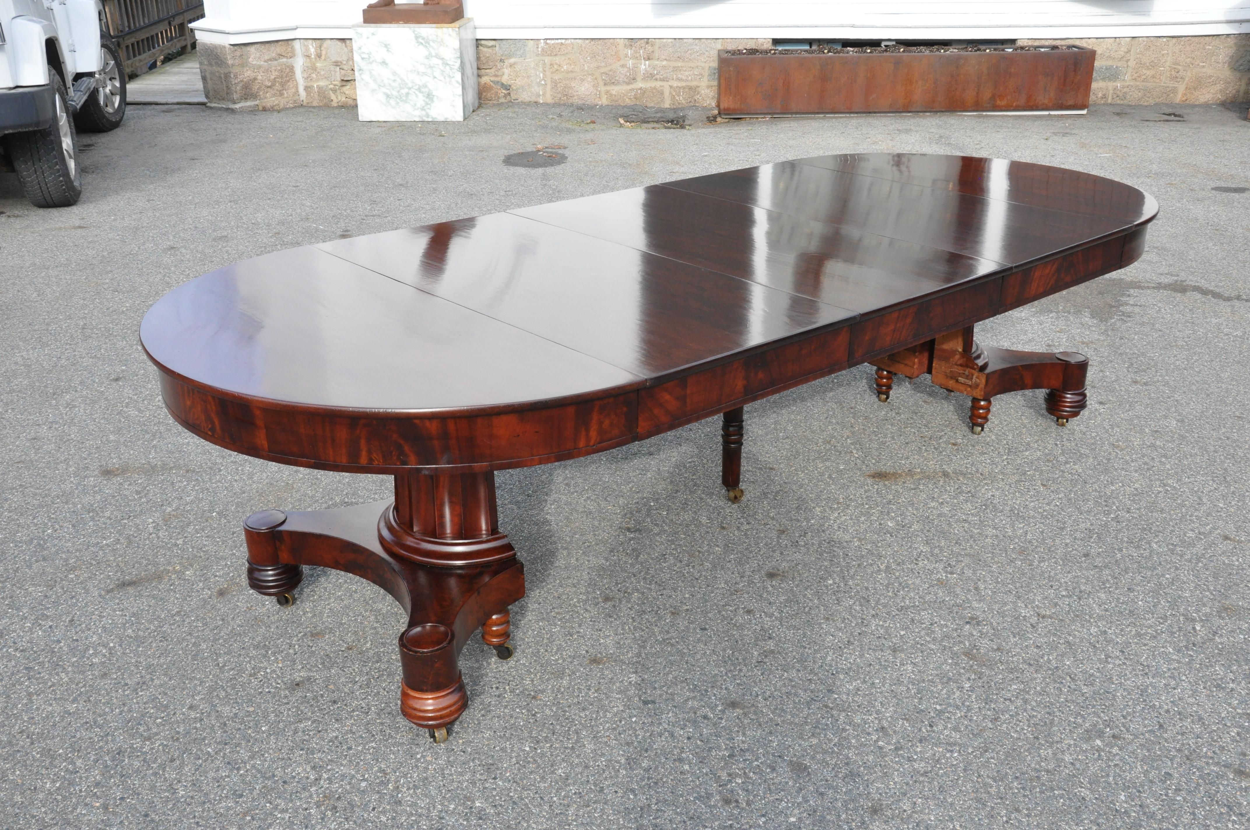 Period early 19th century round dining table with three leaves for expansion
--Tasteful fluted column pedestal with original feet. Crotch grain mahogany and solid mahogany top.
Three leaves with aproned sides. Boston Empire or late Federal
