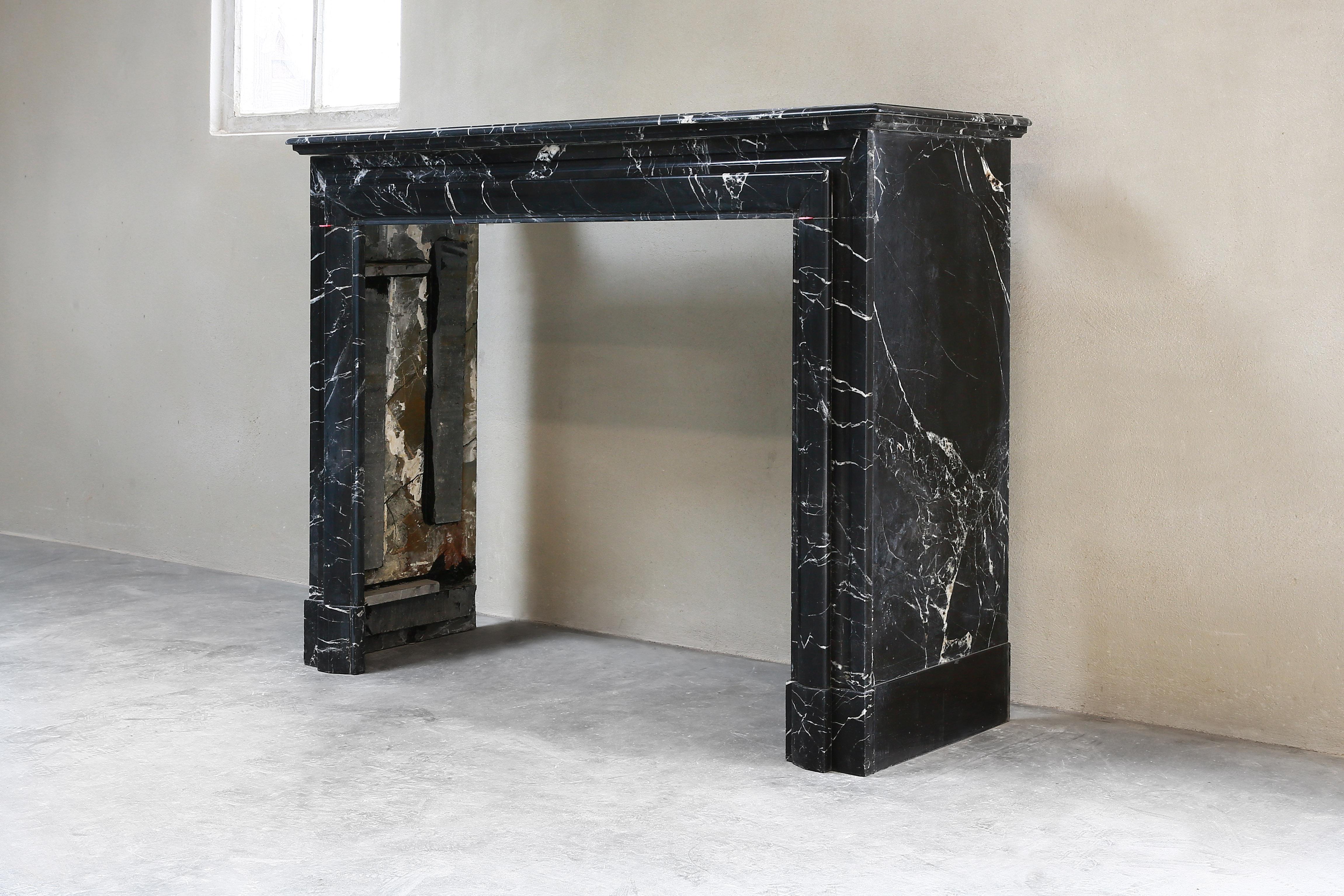 A very beautiful antique fireplace of the marble type Nero Marquina, a black marble with light veins. This fireplace dates from the 19th century and is in the style of Boudain. The fireplace is sleek with beautiful lines and can be used for many