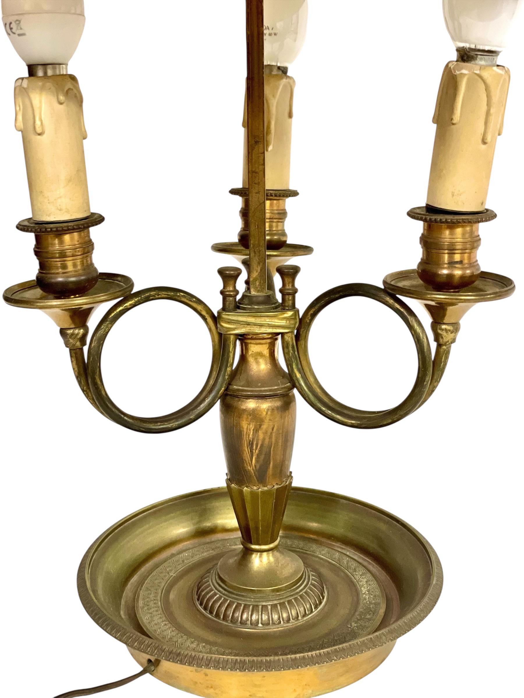 Esta lámpara bouillotte francesa del siglo XIX es un distinguido ejemplo de diseño neoclásico, elaborado en bronce con una pátina finamente envejecida. La base circular, ricamente detallada con delicados grabados, sostiene un balaustre central y