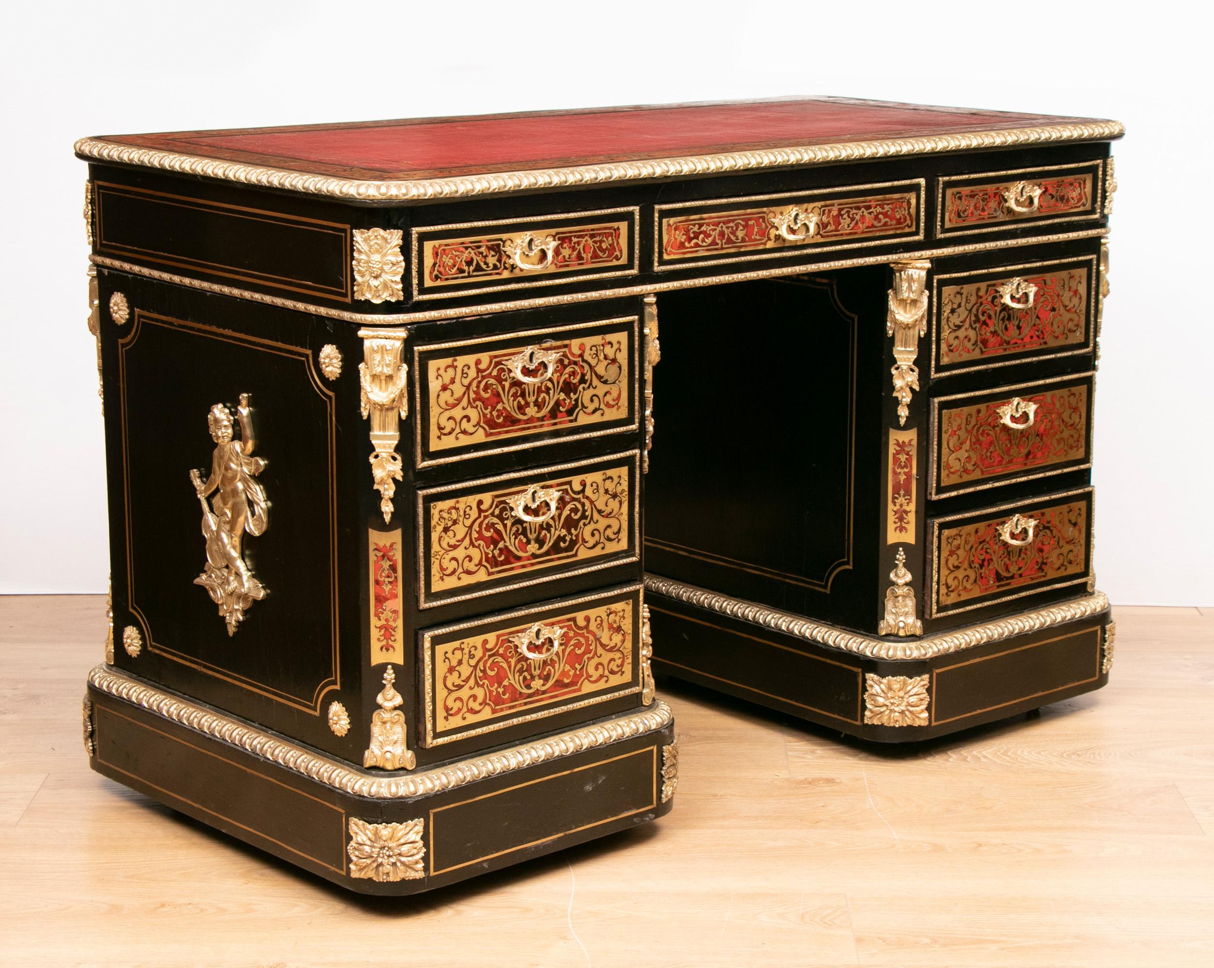 A very distinctive ebonized desk, inlaid with engraved brass on red tortoiseshell panels. Decorative gilt metal mounts demonstrate outstanding craftsmanship. The top has three frieze drawers and red leather writing surface. There are three further