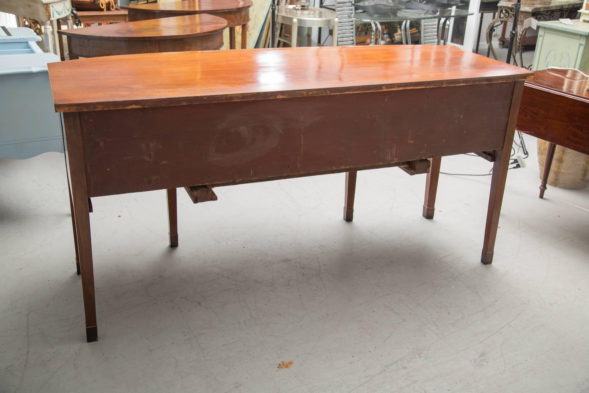 This graceful mahogany sideboard has a bowfront top over a conforming case containing a long central drawer above a recessed drawer and flanked by two cupboard doors. The entire case piece is supported by straight tapered legs, 19th century.