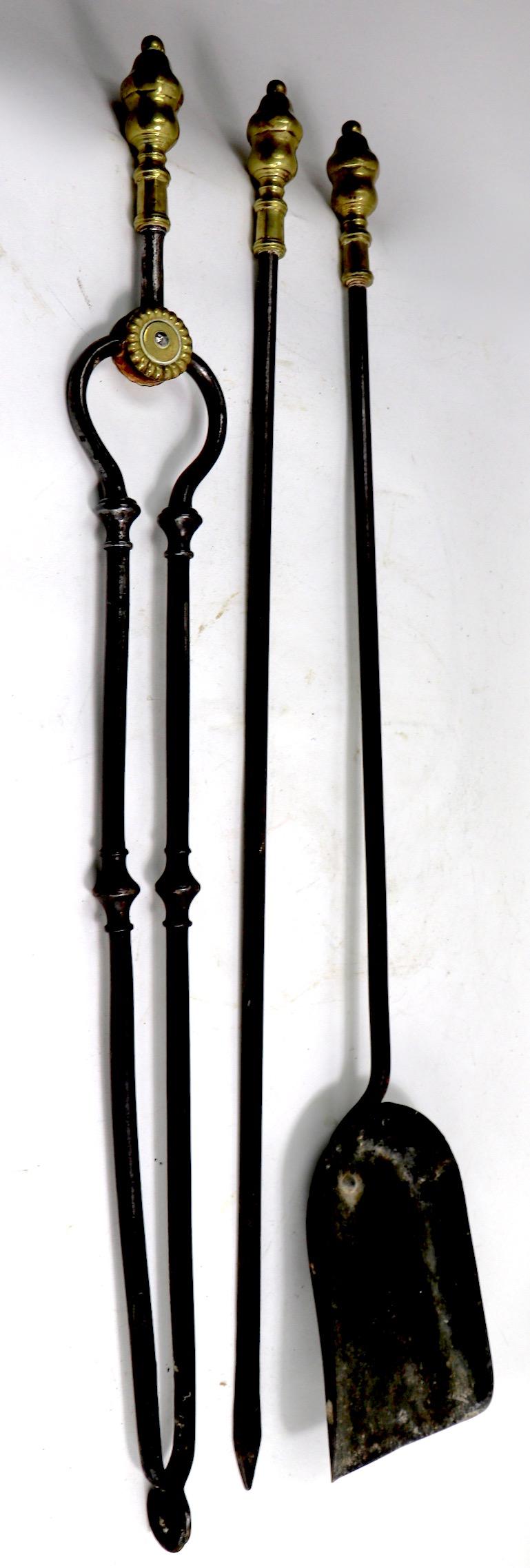 Hand forged iron, and cast brass fireplace tool set to include stand, tongs, poker, and shovel. Well crafted, substantial set, in original, clean and ready to use condition. We believe this set is English in origin, however it is unsigned.