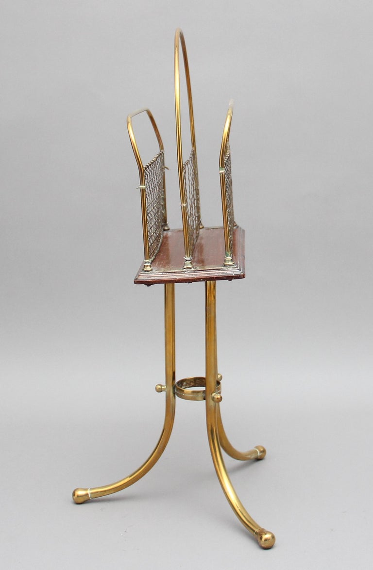 A nice quality 19th century brass and mahogany magazine rack with two divisions, the brass rods have got nice brass wire work panels, standing on three swept legs united by a brass collar attached with decorative brass bolts, circa 1880.