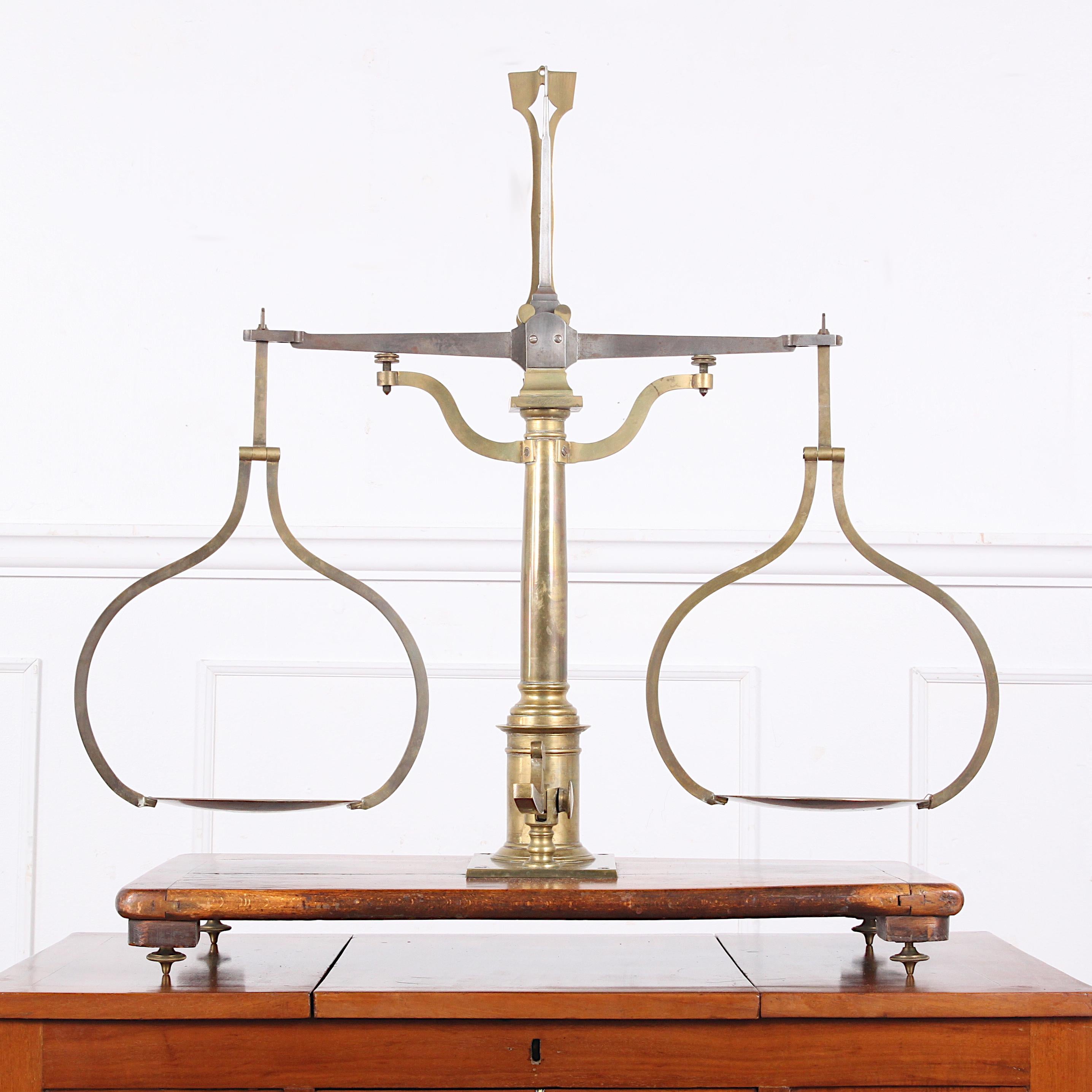 A handsome 19th century brass balance scale on a wooden stand and with a set of weights.