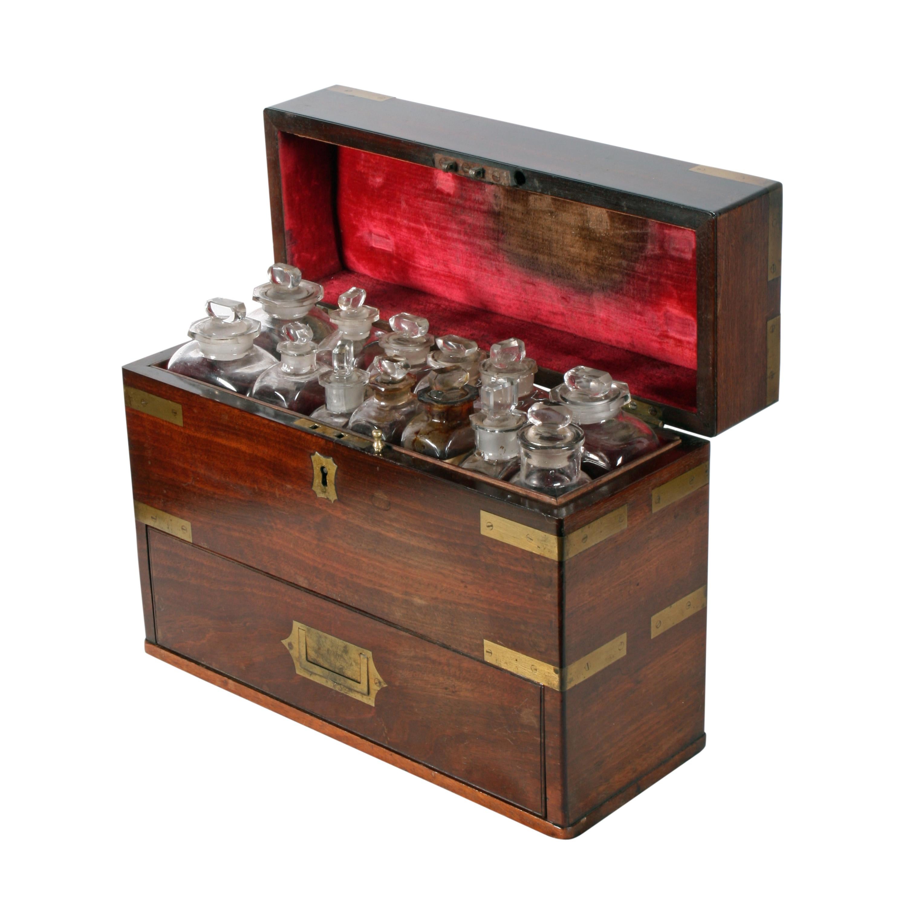 A mid-19th century mahogany brass bound apothecary box or cabinet.

The oblong box has a deep hinged lid and storage compartments that hold thirteen assorted size bottles with glass stoppers.

The bottles are held in velvet lined compartments