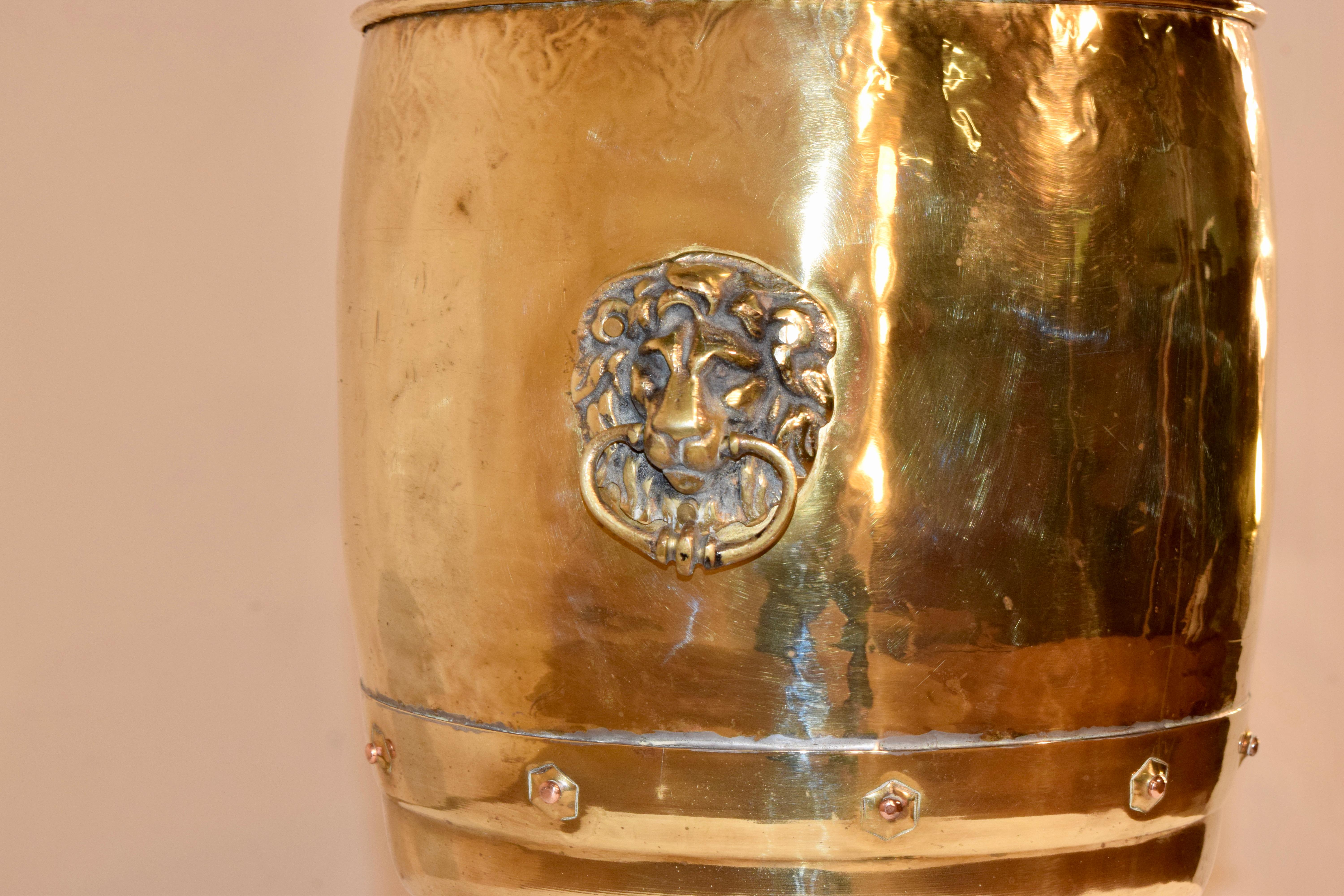 19th century brass coal hod with a rolled edge, banded and decorated with copper rivets. Beautifully hand made with hand cast lion's head handles on each side and supported on hand cast paw feet.