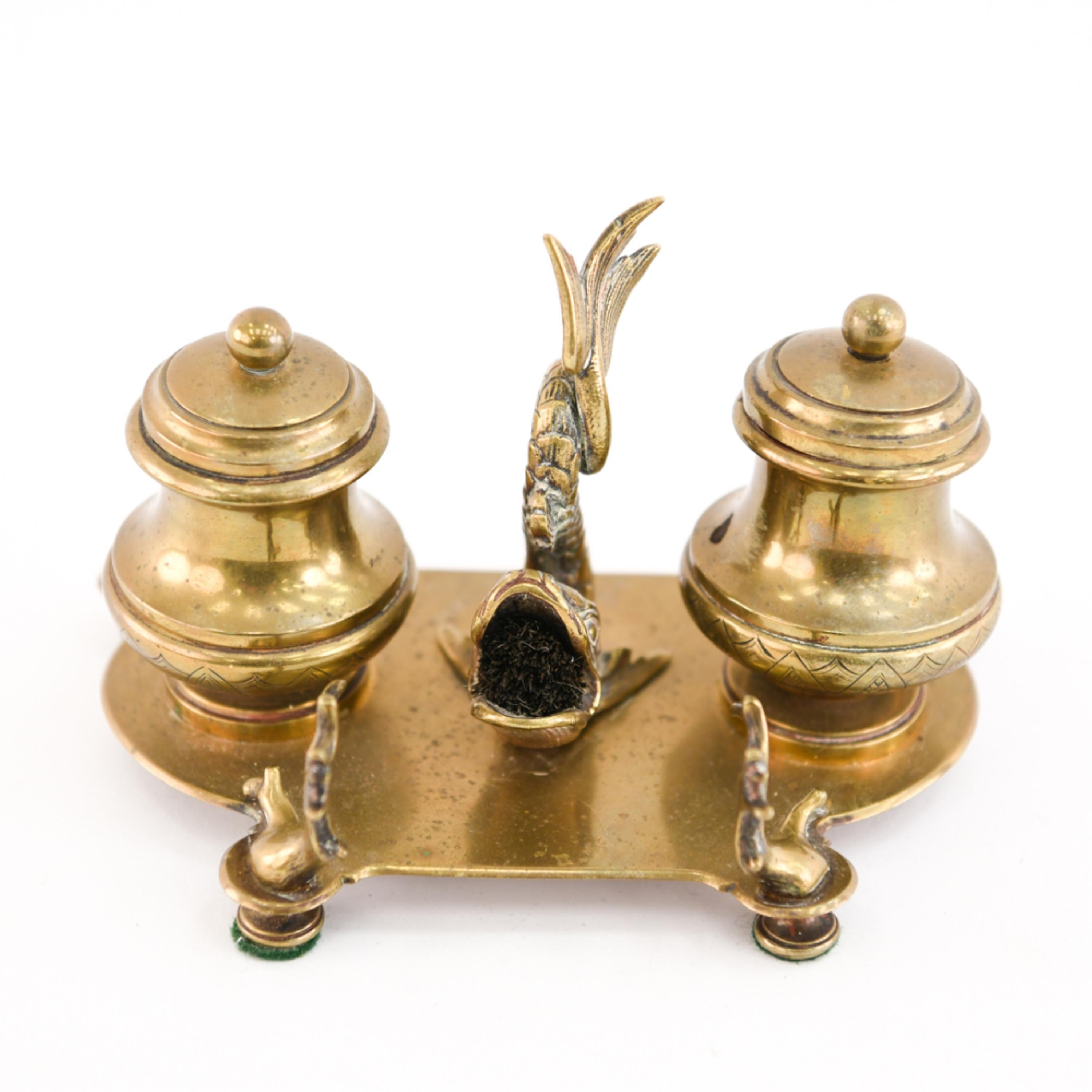 A 19th century brass double inkwell with a central dolphin figure.