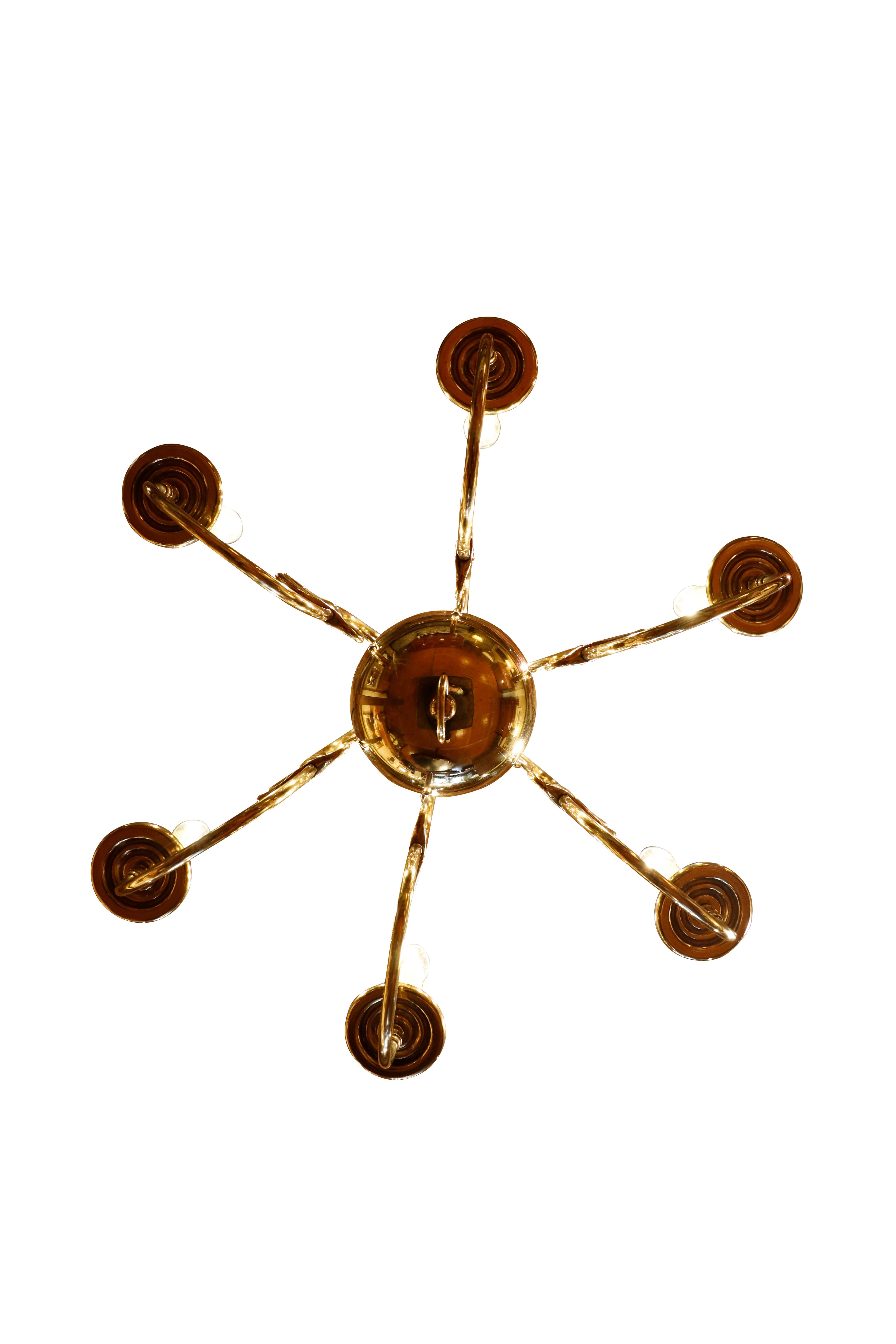 Lampadario a sei bracci in ottone fiammingo.  Il lampadario è sormontato da una doppia aquila e presenta bracci con motivo a delfino.
