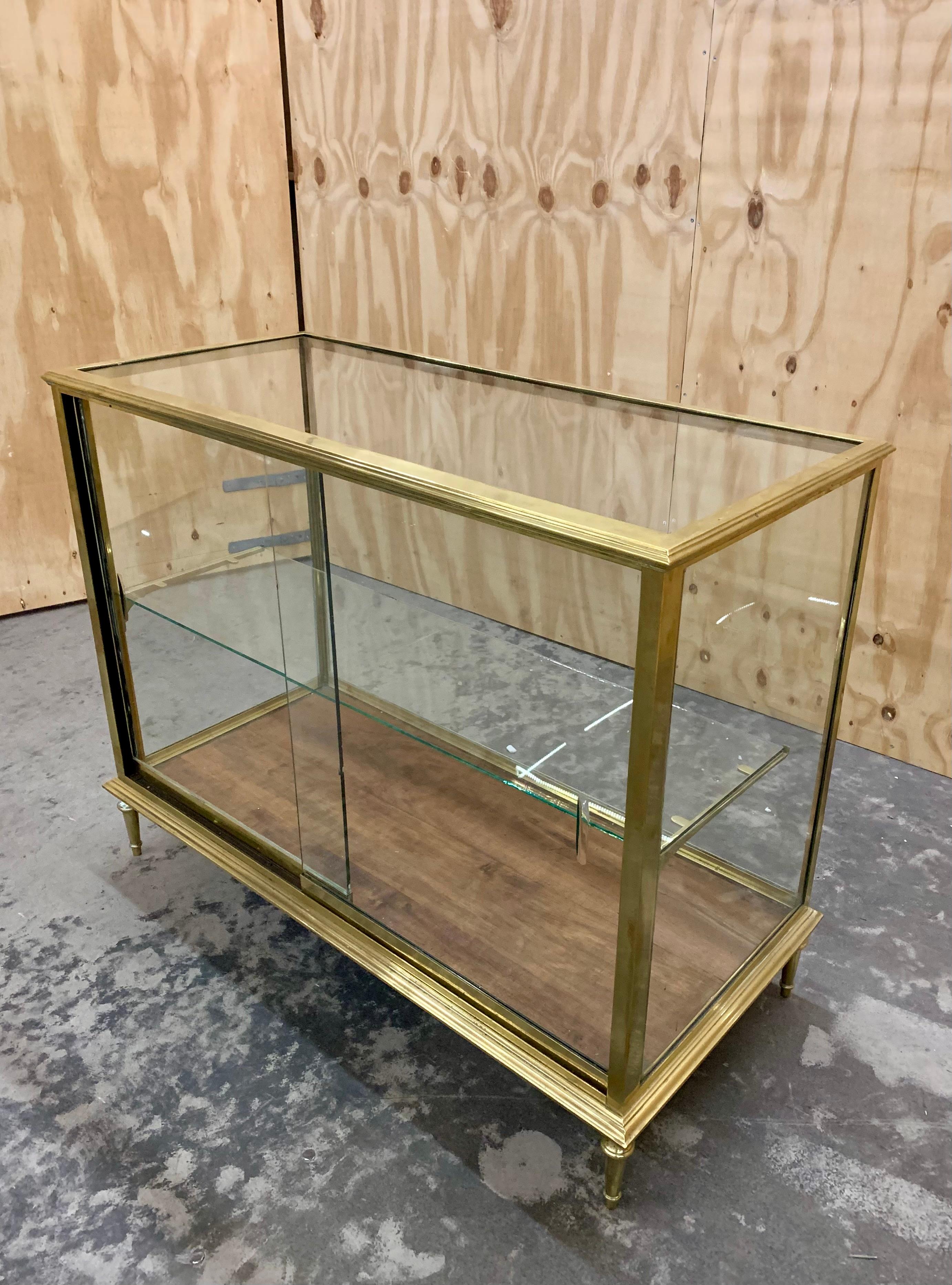 Très joli comptoir ancien en laiton et verre avec une étagère réglable en verre et de très beaux détails en laiton. Le comptoir est en très bon état et présente des traces d'usure dues à l'âge et à l'utilisation.