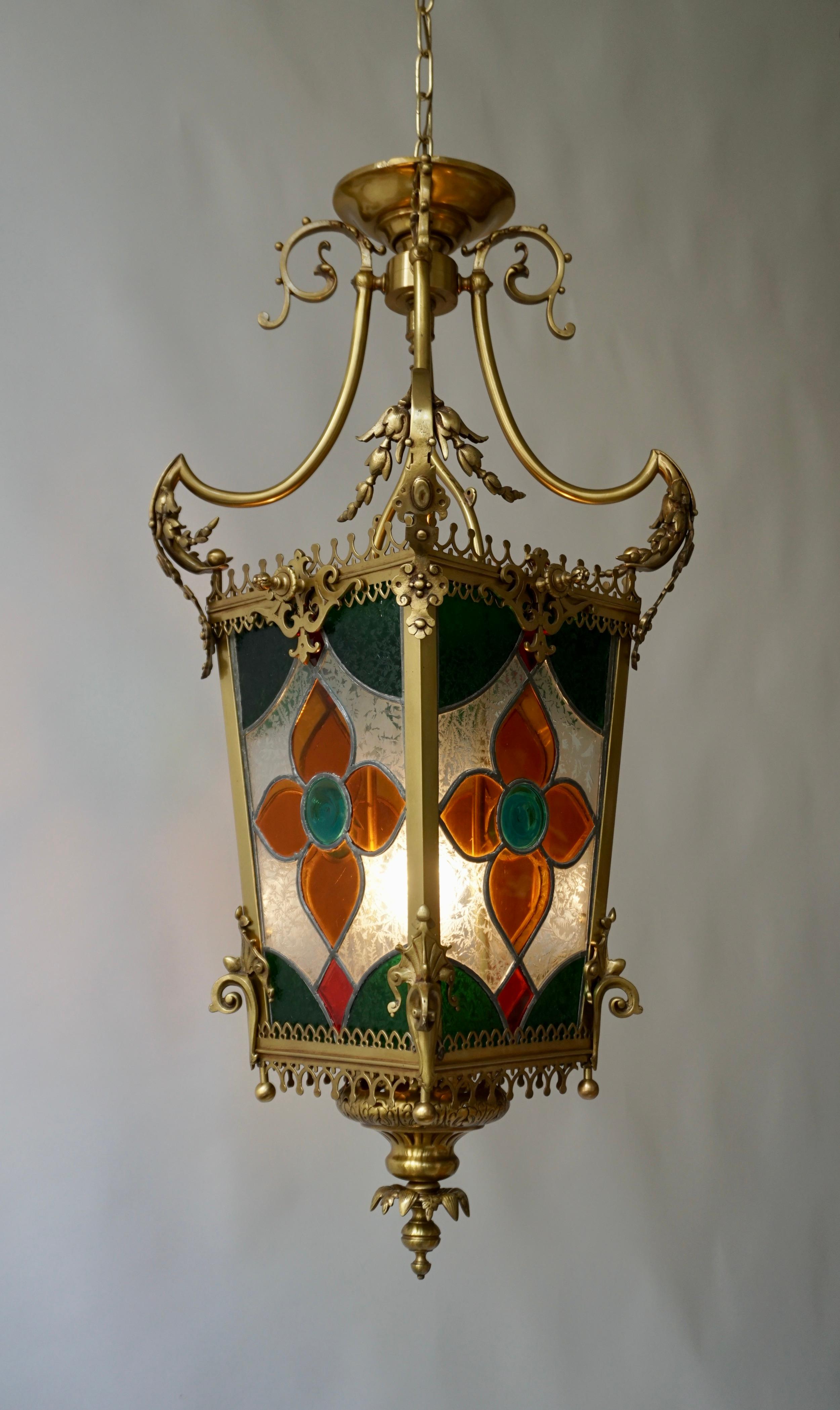 Messing-Hallenlaterne aus dem 19. Jahrhundert mit originalen Buntglasscheiben. 

Die Leuchte hat eine Fassung für Glühlampen mit Schraubsockel oder LEDs vom Typ E27. Es ist möglich, diese Leuchte in allen Ländern (USA, Großbritannien, Europa, Asien,
