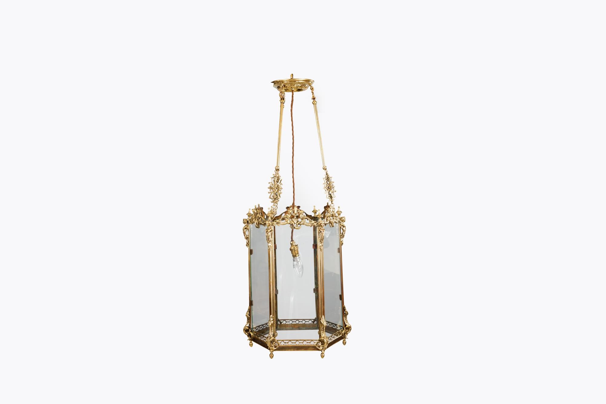 19th Century brass hexagonal hall lantern heavily decorated with neoclassical style figureheads, sea creatures and mermaids to the upper section, and terminating with naturalistic scrolling and stylised acorn finials below.