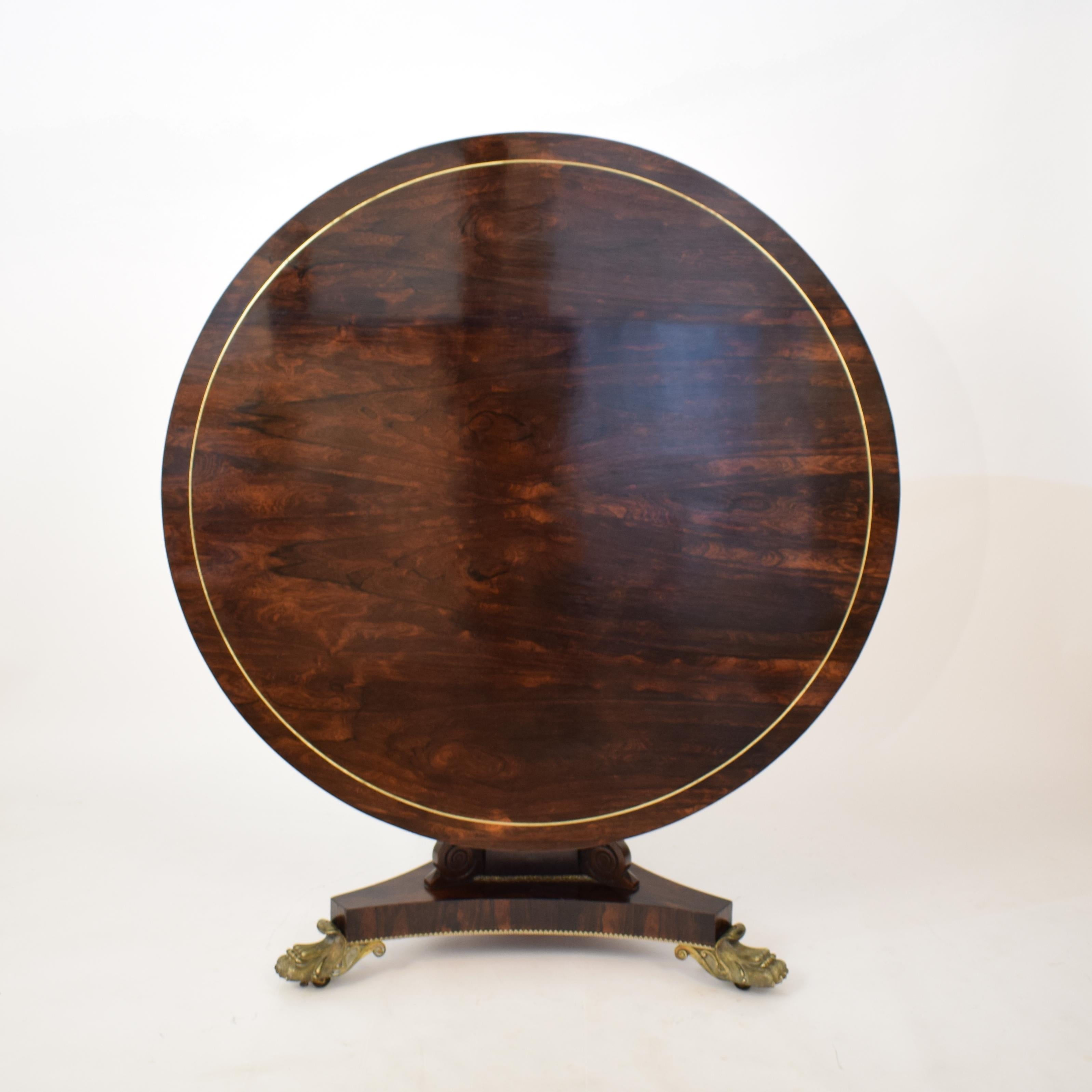 This beautiful 19th century George IV brass inlaid rosewood centre table circa 1840s is attributed to Gillows of Lancaster & London.
The table is made out of solid Mahogany and veneered in rosewood.
It has a circular tilt-top with brass string