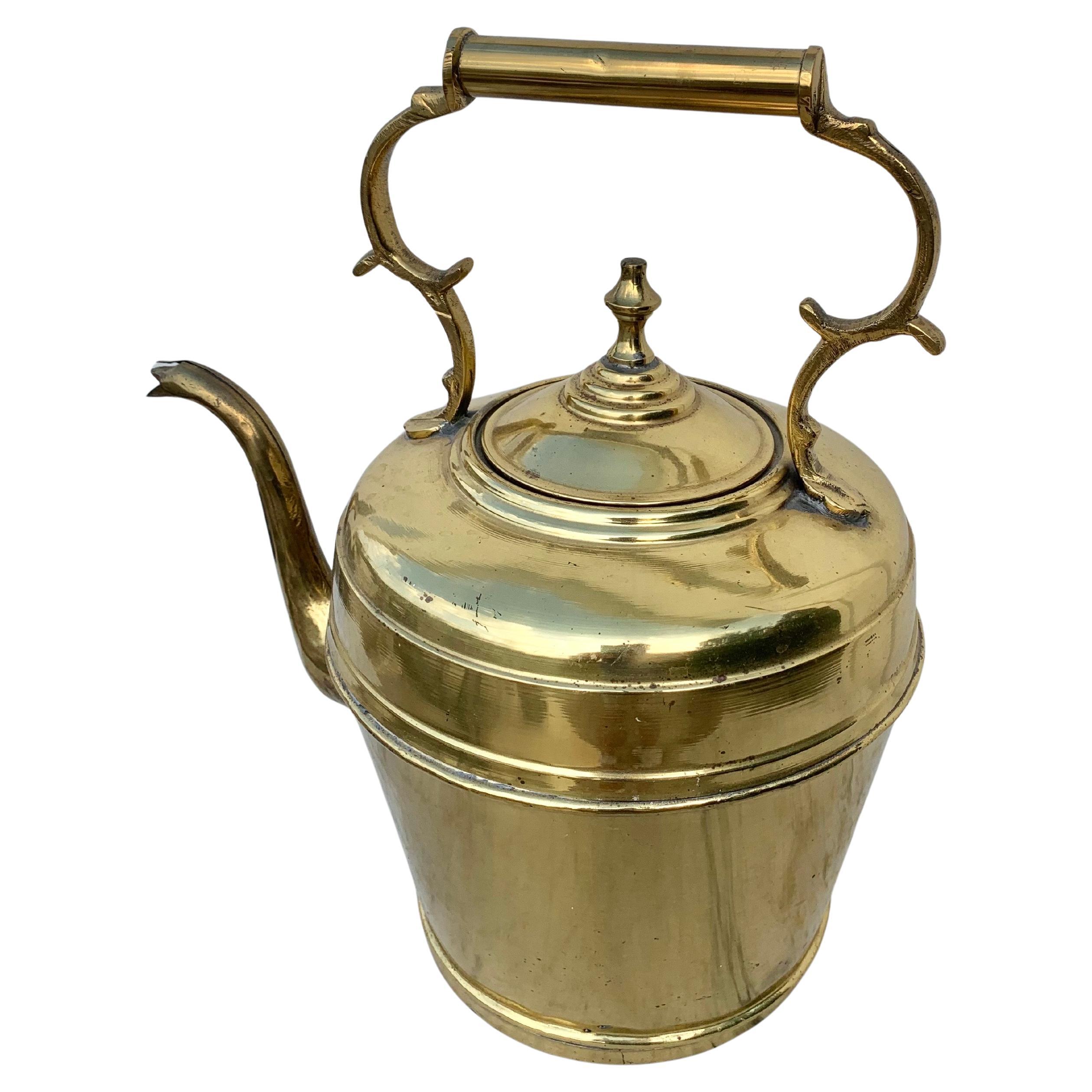 Cette bouilloire du XIXe siècle a été fabriquée en laiton par des artisans à la fin des années 1800. La pièce comporte une poignée aux détails complexes qui mène à une bouilloire surdimensionnée. Les coutures sont toutes soudées à la main et le