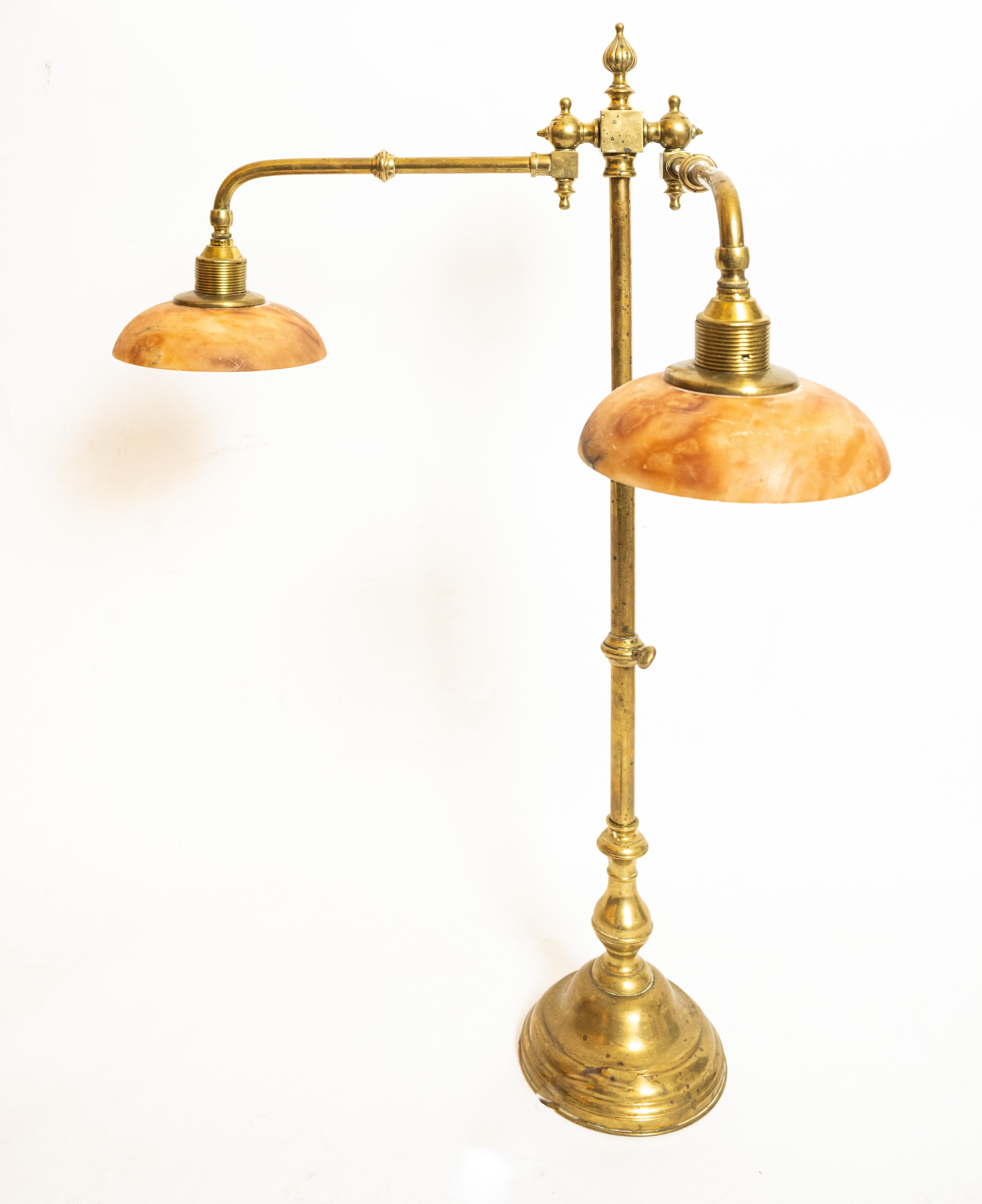 Late 19th-Century English library table lamp. The round base supporting a stem with baluster shaped elements. The two arms are adjustable and fitted with caramel colored turned alabaster shades. The finish features a light patina. 2 sockets, each