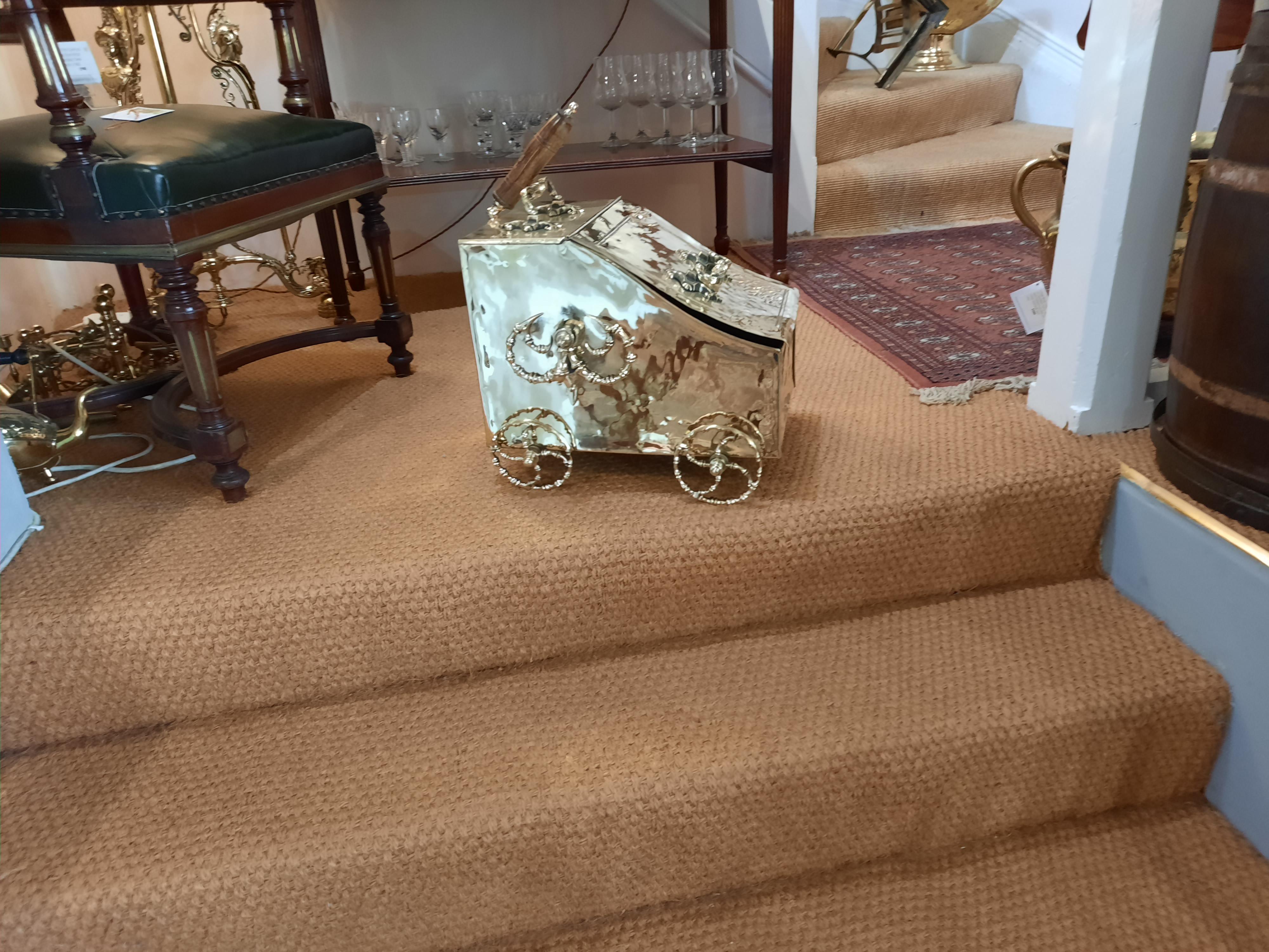 19th Century brass novelty coal purdonium, in the form of a twin axle carriage, applied with two 'C' scroll swing handles and side droplet handles, raised upon four spoke cart wheels measures: 18