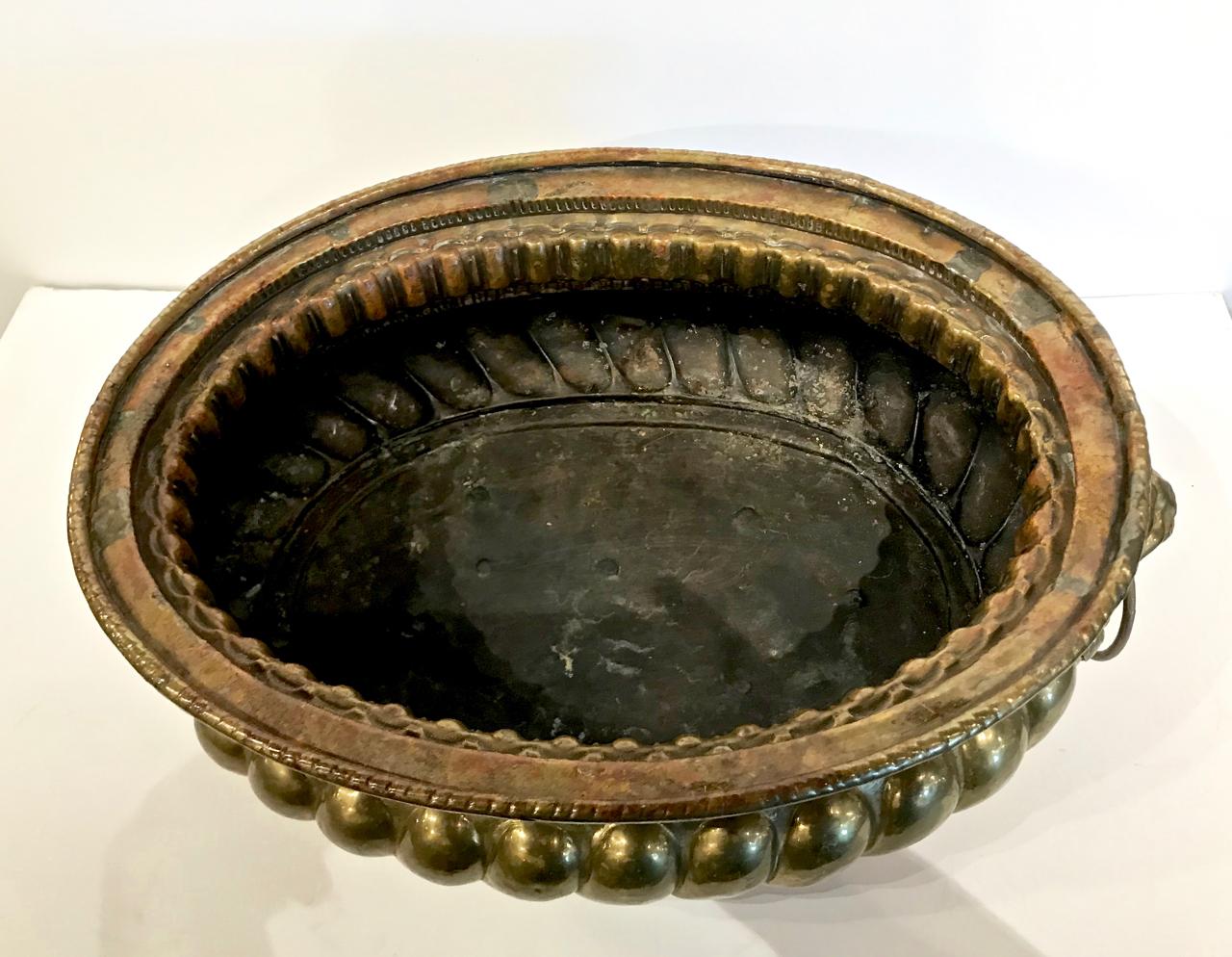 This is a very decorative and detailed 18th/19th century Dutch brass wine cooler/planter or jardinière. The planter is detailed with high relief lion's head end handles and lion paw feet. In addition to functioning as a standout wine cooler, this
