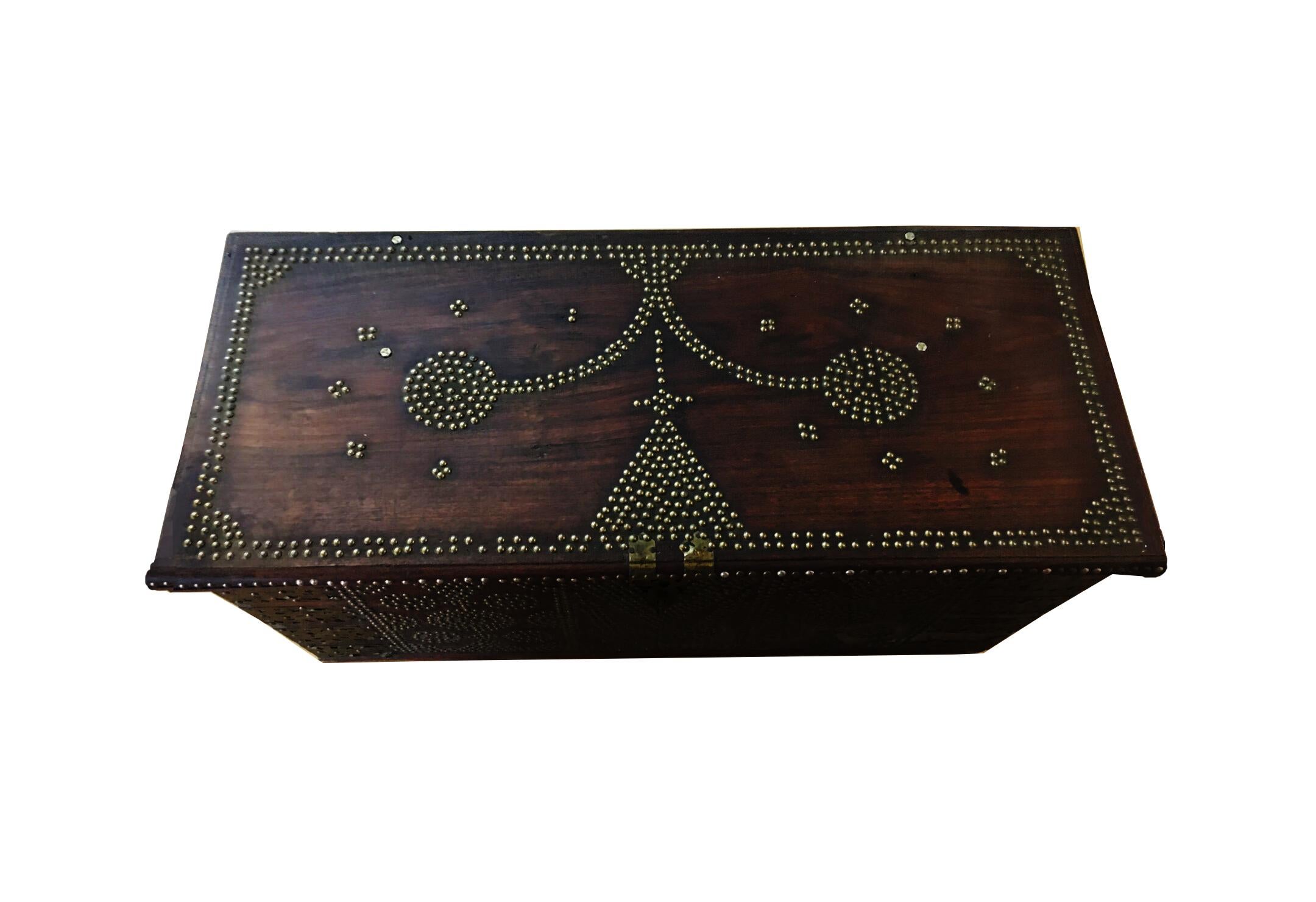 A stunning rare 19th century Zanzibar or Bombay chest composed of six thick slabs of teak wood. The exterior of the trunk is outfitted with brass sheets and studs in geometric patterns, particularly pyramidal shapes mounted by crosses, representing
