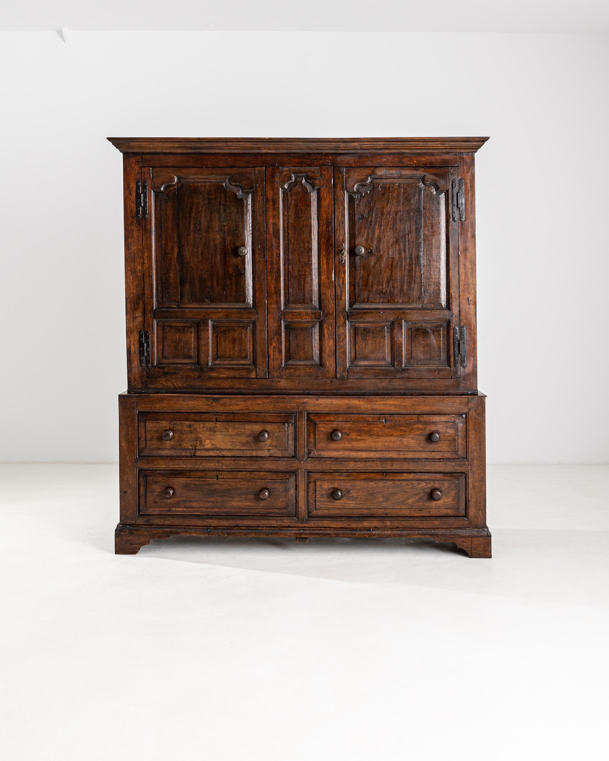 A 19th century wooden cabinet produced in the United Kingdom, flaunting an opulent auburn finish and a luscious natural patina. The lower case is fitted with four elegant and practical front drawers, adorned by rounded wooden knobs and topped by an