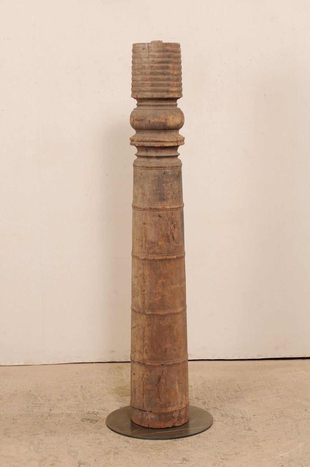 A single 19th century British Colonial carved wood column with custom stand. This antique hand carved wooden architectural element from India, which stands just over 5.5 feet in height, features a rounded column adorn with a series of carved rings