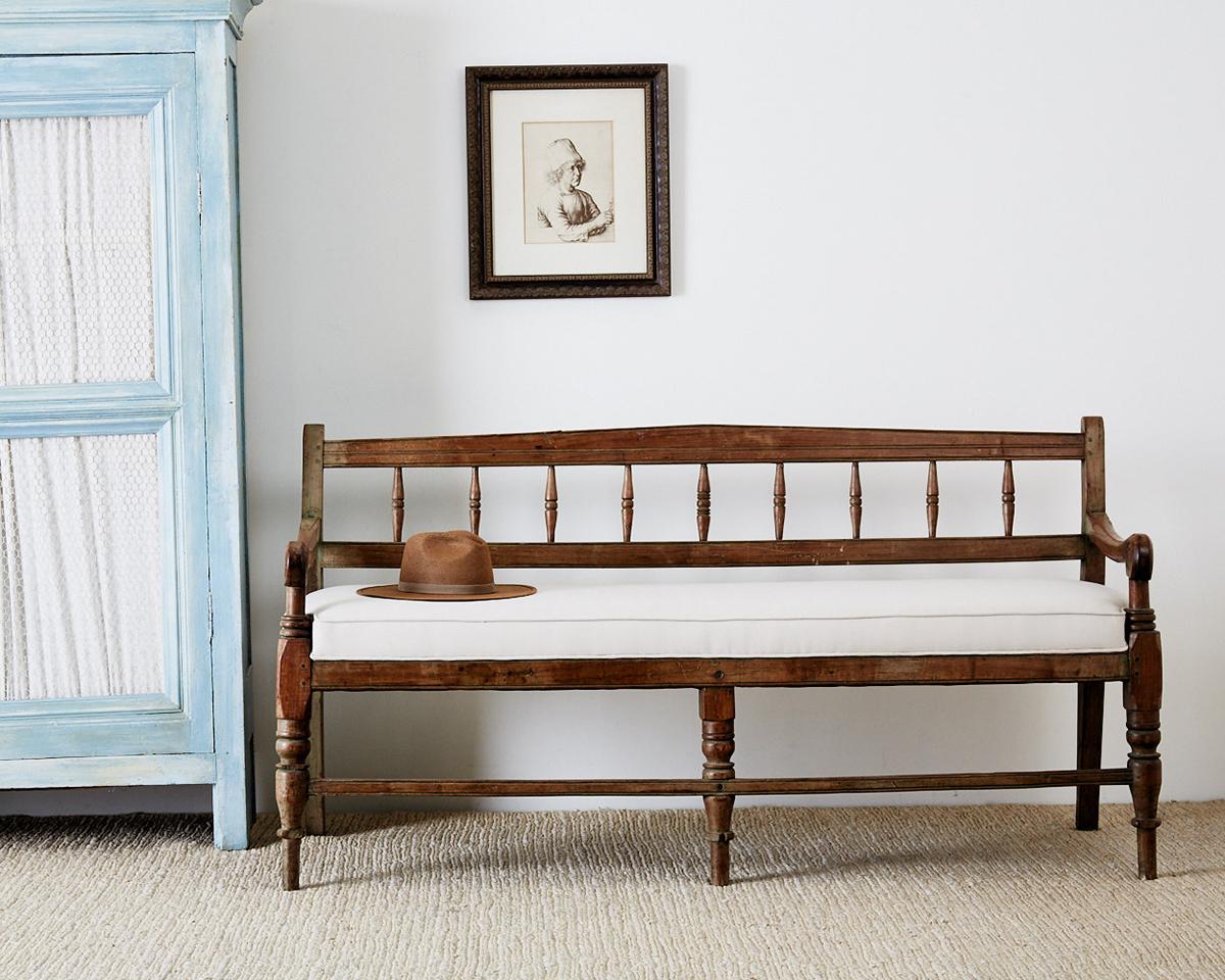 19th century teak plantation bench made in British Colonial India. Beautifully hand carved with wood peg joinery and a lovely faded patina. Newly upholstered using an organic cotton fabric. The backrest features turned spindles and the large arms