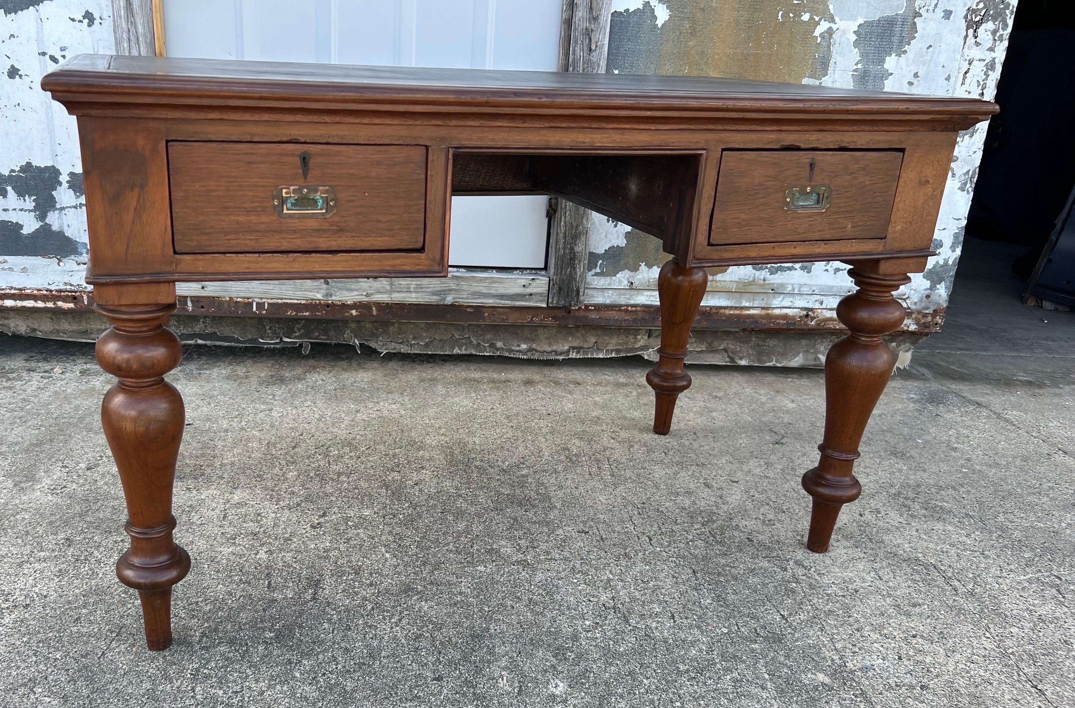 19th century British colonial campaign style leather top desk with turned legs, campaign pulls and leather top over three drawers. Finished on all sides with a 26” knee clearance.