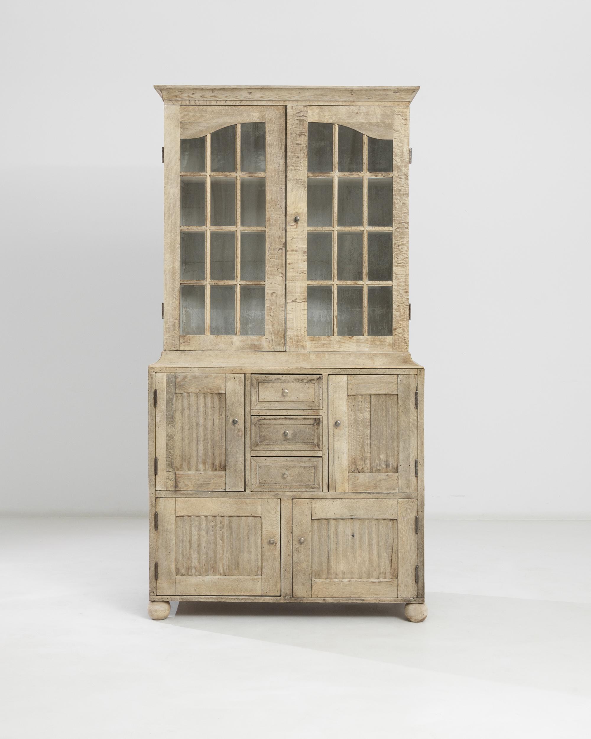 This vintage oak vitrine makes a charming country accent. Built in Great Britain in the 19th century, the ridges of the paneling evokes the bygone flurry of washboards on laundry day. Mullioned windows offer a view onto a trio of interior shelves,