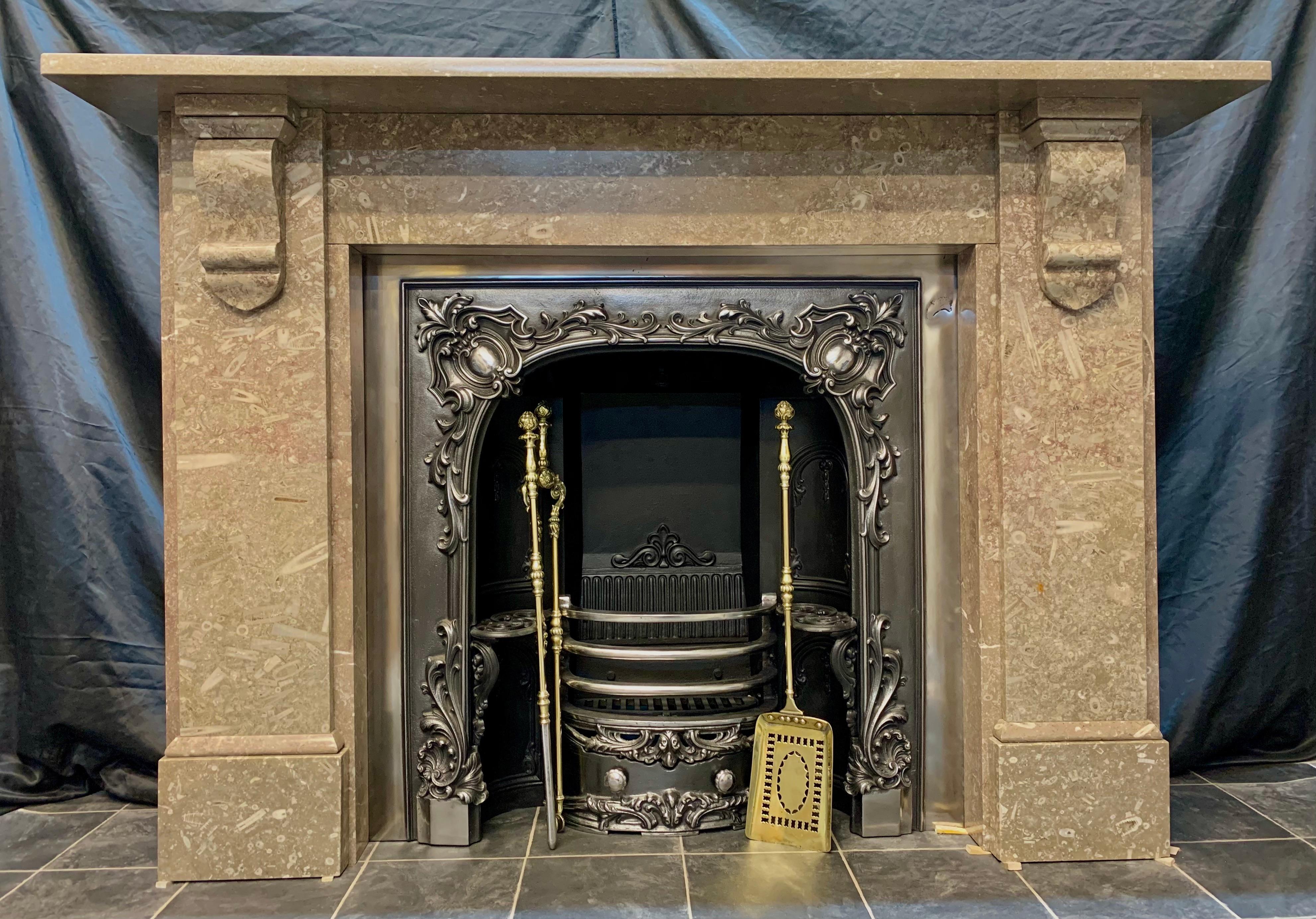 A large 19th century British Swaledale marble fireplace surround in soft mushroom tones with many different types of fossils, a substantially deep shelf sits above an unadorned frieze, flanked by wide stepped jambs displaying geometric corbels with