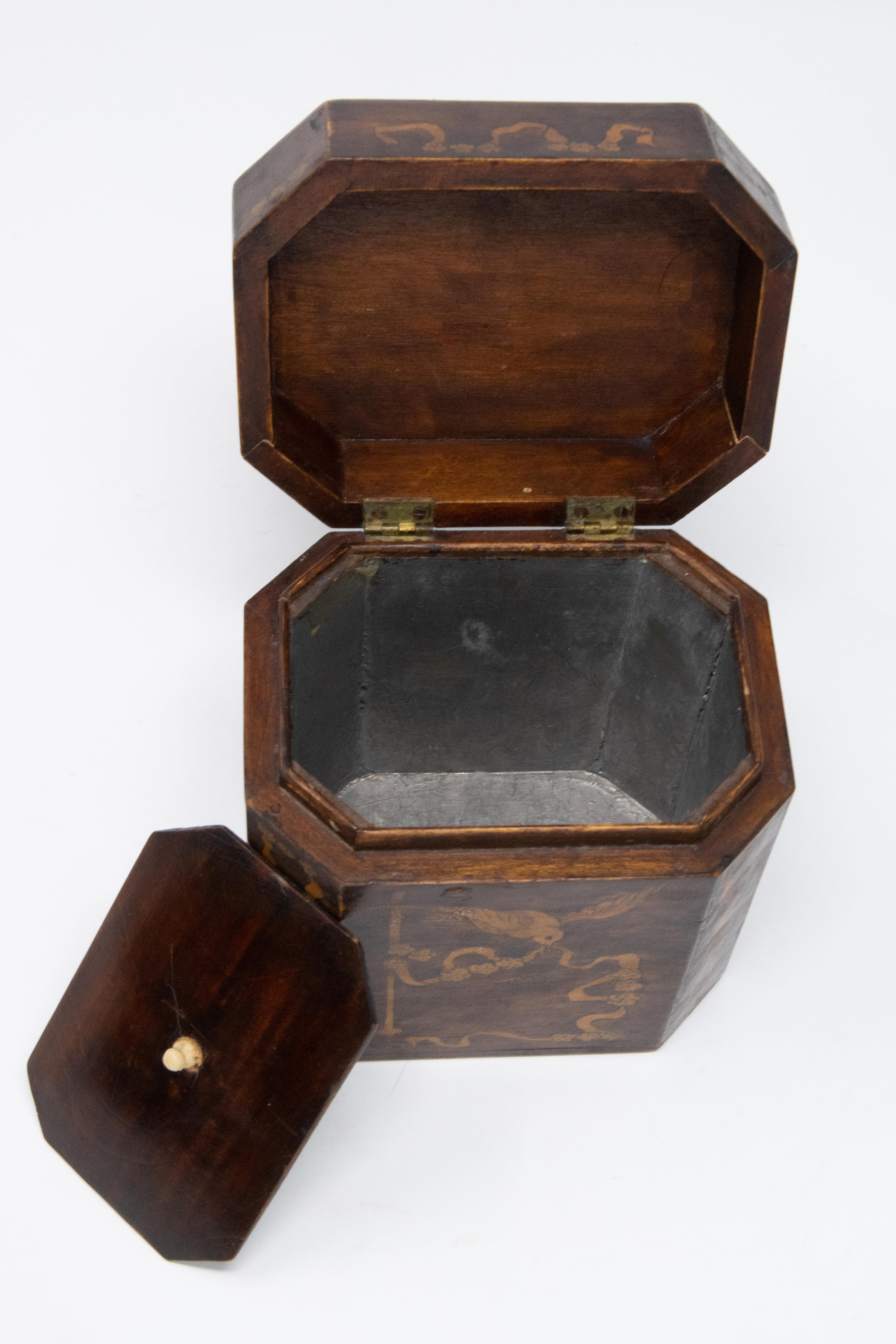 This beautiful tea caddy has extensive inlay depicting ribbon, floral, and birds. The canted corners on this box give it a different dimension. Lidded interior with zinc lining are still present on this piece.