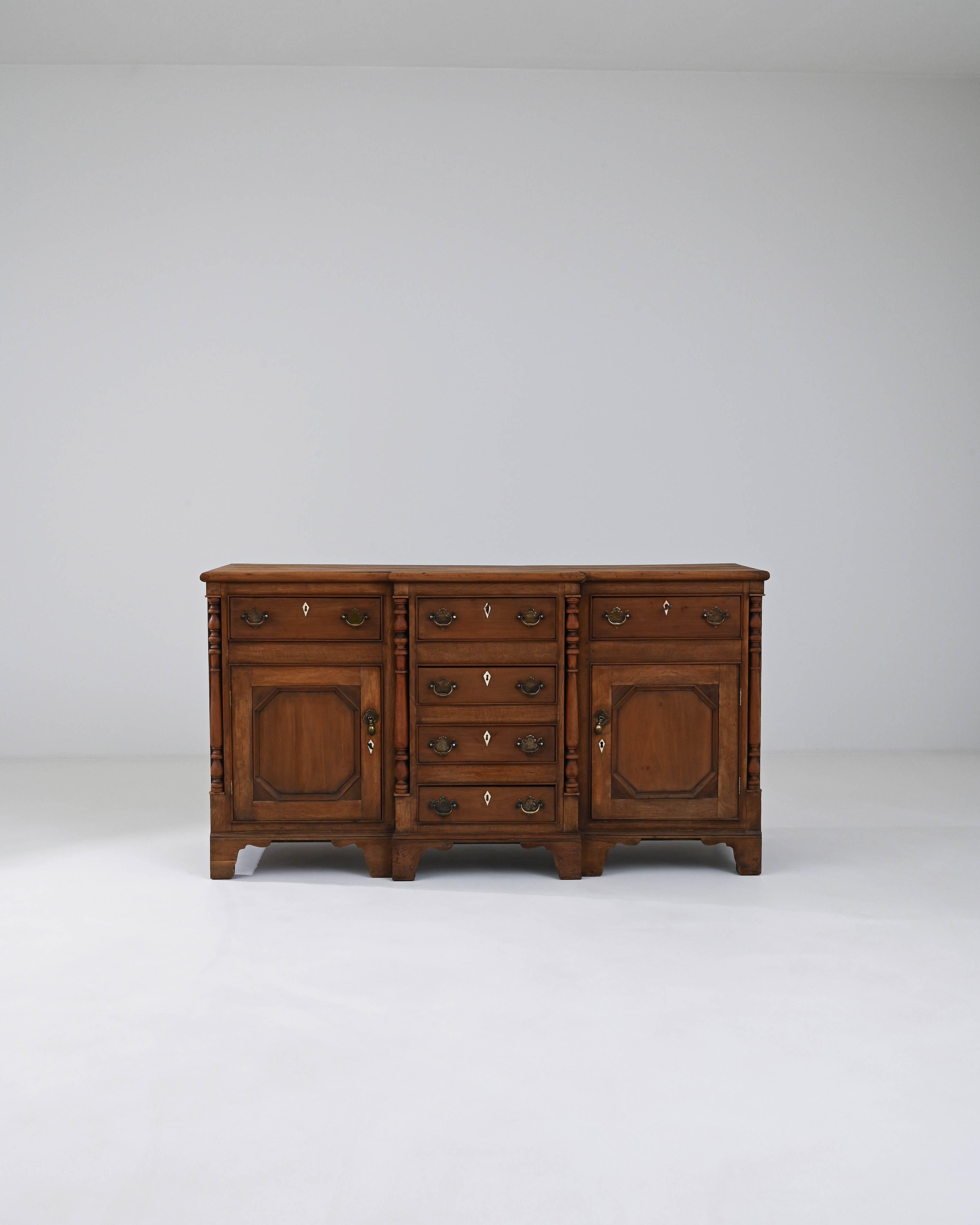 This 19th Century British Wooden Buffet exudes the charm and robust grace of the period. A harmonious blend of utility and style, it features a solid wooden structure that tells the story of its age with a warm patina that only time can bestow. The