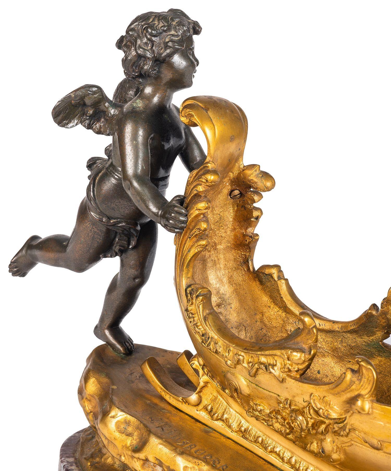 An enchanting 19th Century patinated bronze and gilded ormolu cherub pushing a sleigh with a butterfly mounted on the front, set on a rouge marble plinth.
Signed; S. Kinsburer.

Batch 74 G9941/23 SNYZ