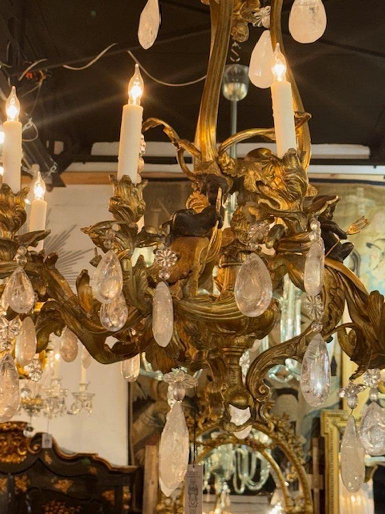 Questo lampadario rococò del XIX secolo in bronzo e cristallo di rocca presenta dettagli intricati con cherubini, che aggiungono un tocco di eleganza e fascino a qualsiasi spazio. La combinazione di materiali in bronzo e cristallo di rocca ne esalta