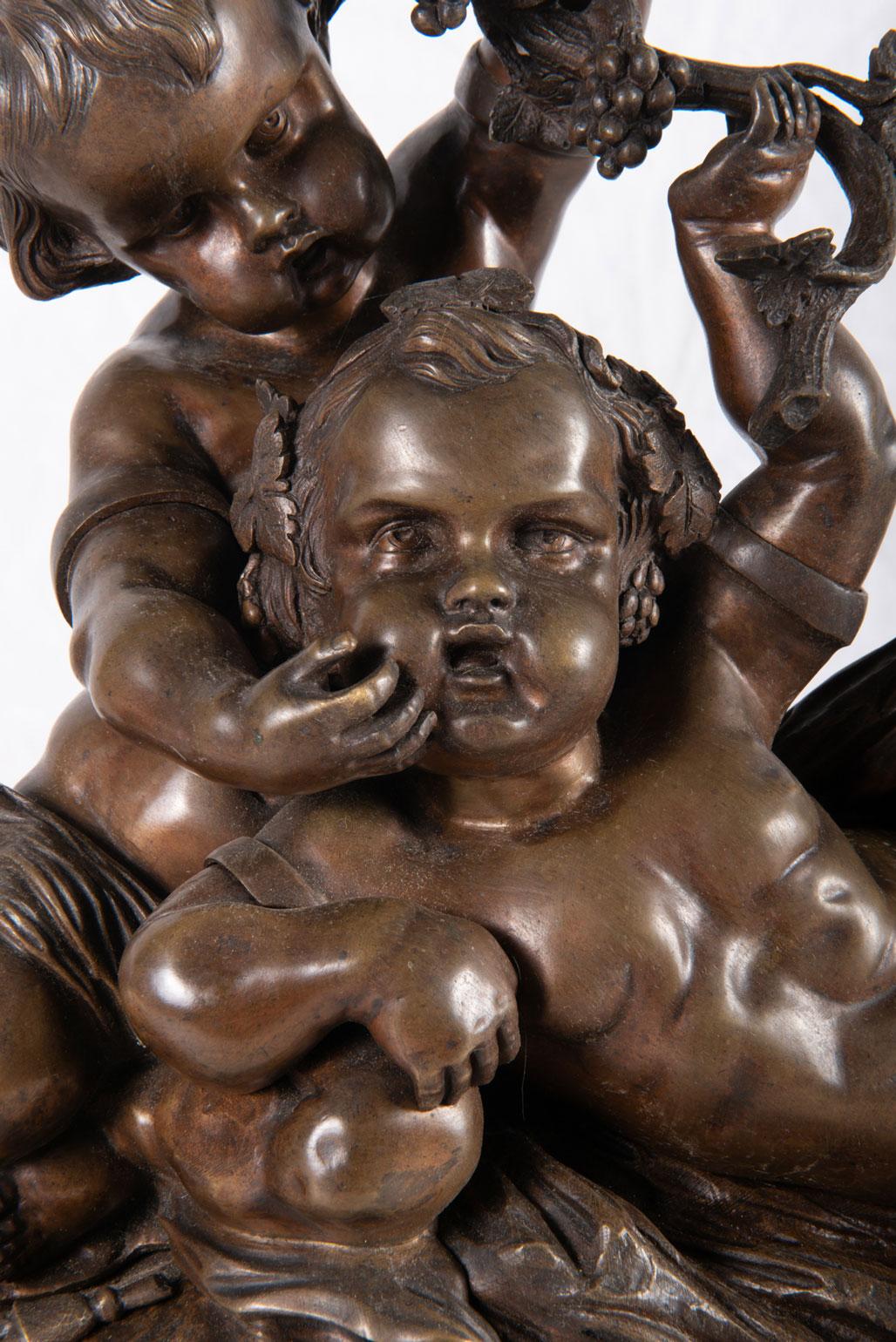 A classical 19th century bronze group of two young putti playing on the ground amongst grape vines.