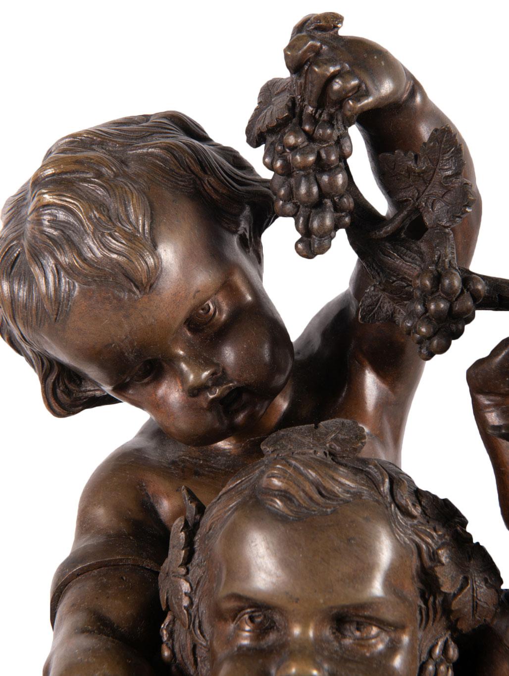 a bronze grouping with a putti standing beside him playing a flute