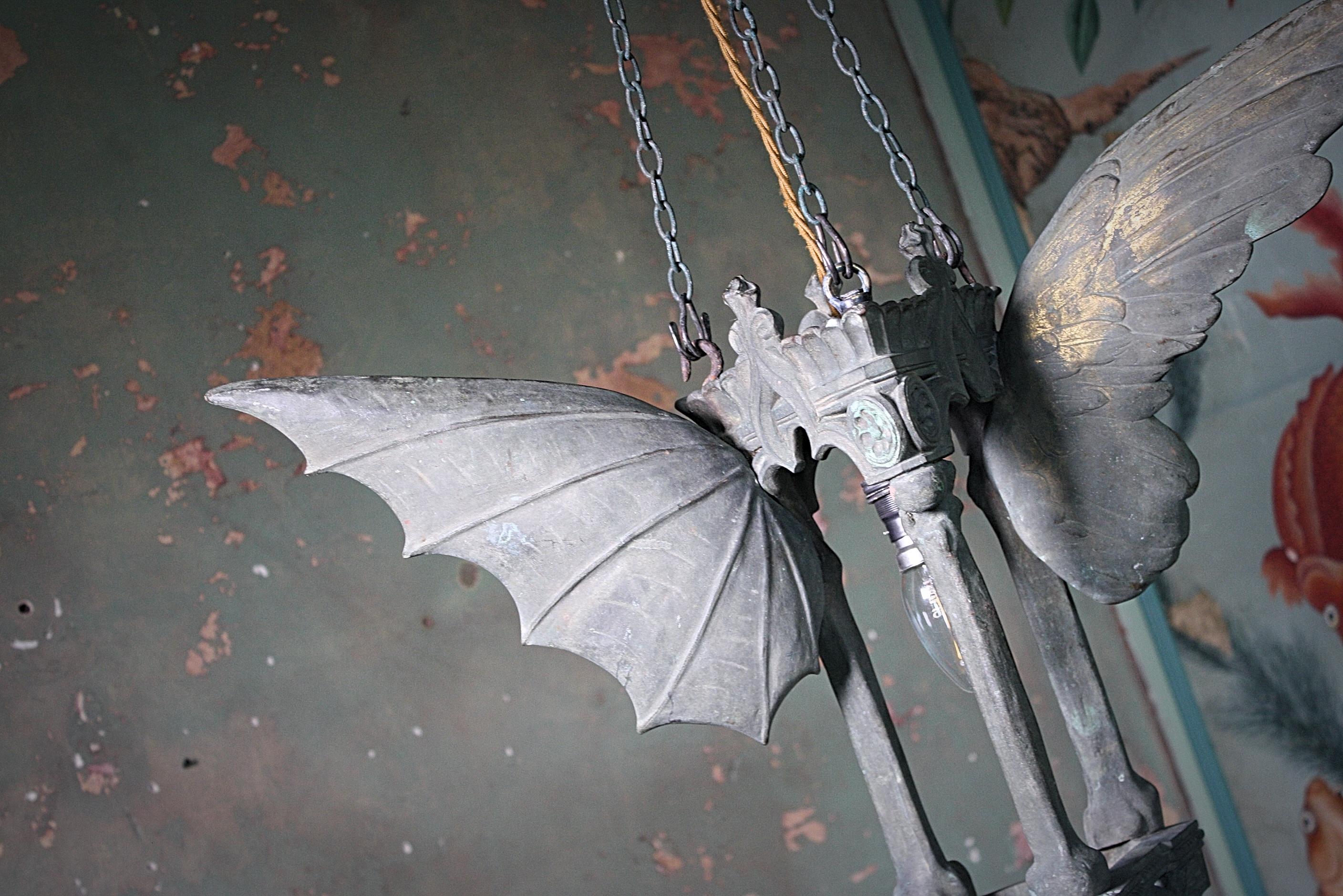 A rather odd crypt lantern, cast in bronze the shapely triangular platform has three bone columns raising up to an arched Gothic frieze. Either side the wings of a bat and angle reside fully stretched symbolising the end of life and passing to