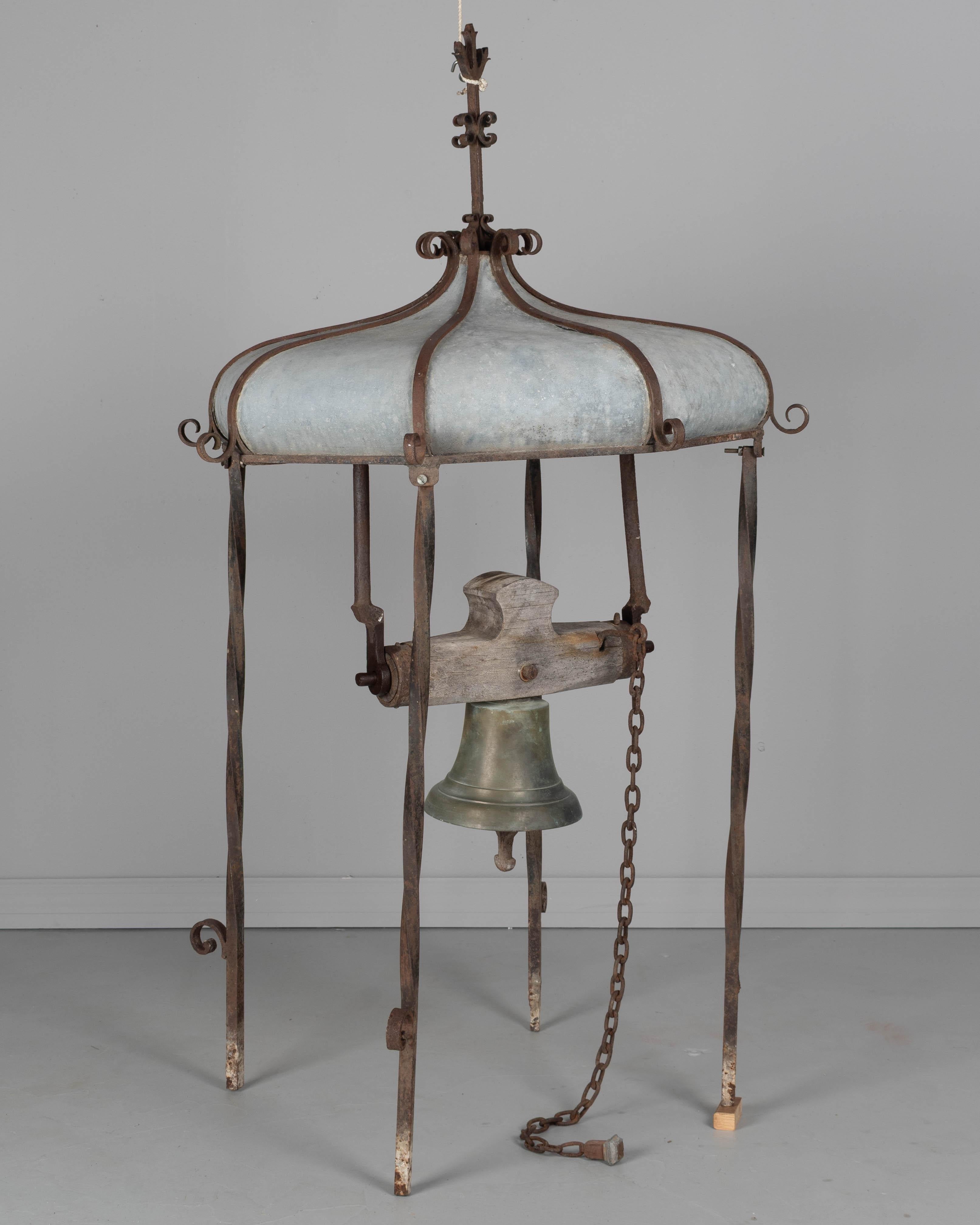 Cúpula francesa del siglo XIX de un campanario de azotea que alberga una campana de bronce fundido. La cúpula tiene un armazón de hierro forjado con tejado de zinc. La campana cuelga de un yugo de madera y tiene una cadena de tiro de 36