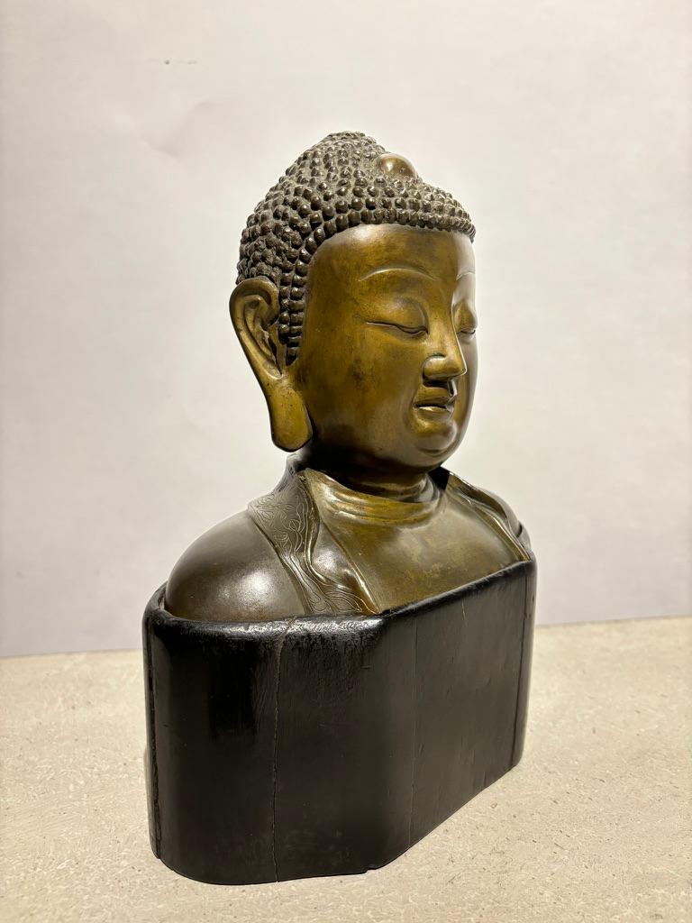 19th century bronze bust of Buddha on the original hand carved custom base. The pleasing proportions, subtle smile, and tranquil eyes of this bust of Buddha make it a beautiful example of physical embodiment of the spiritual. Every home should have
