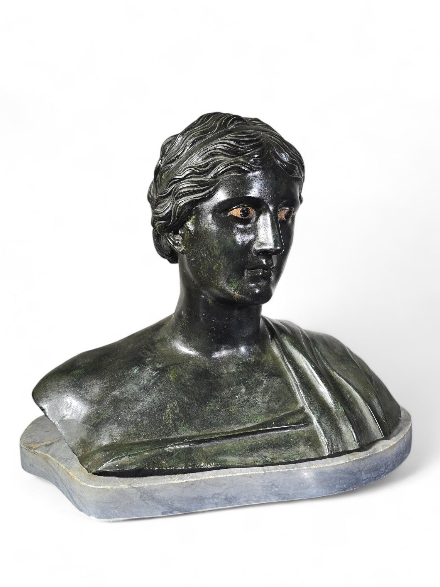 e buste en bronze sophistiqué représente la poétesse grecque Sappho (620 A.I.C. - 550 A.C.), connue pour ses poèmes lyriques. Réalisé en bronze patiné vert foncé avec des yeux en plâtre, le buste est une reproduction fidèle de l'original trouvé dans